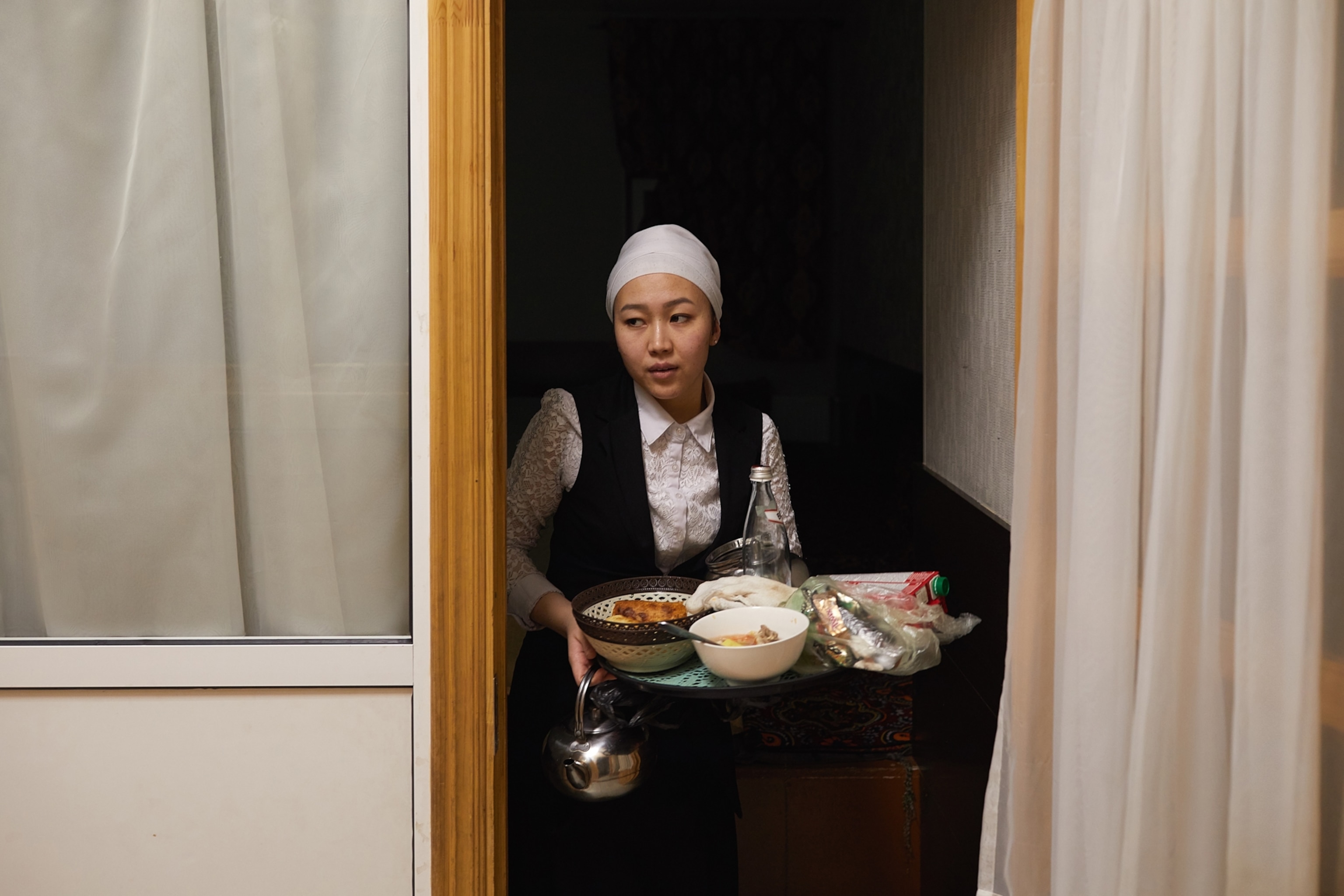 a woman walking through a doorway carrying a tray