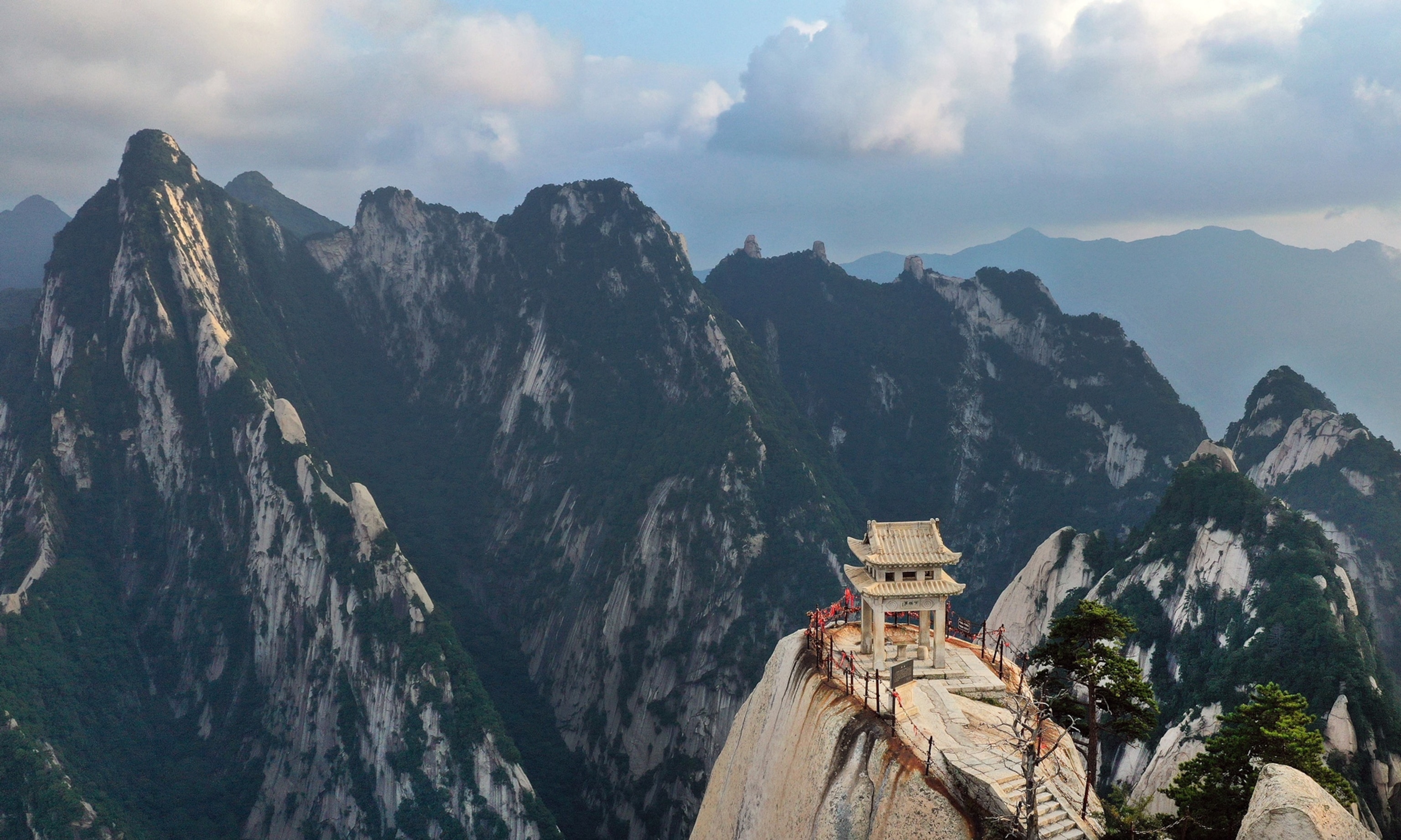 Photo of small structure surrounded by dramatic mountains