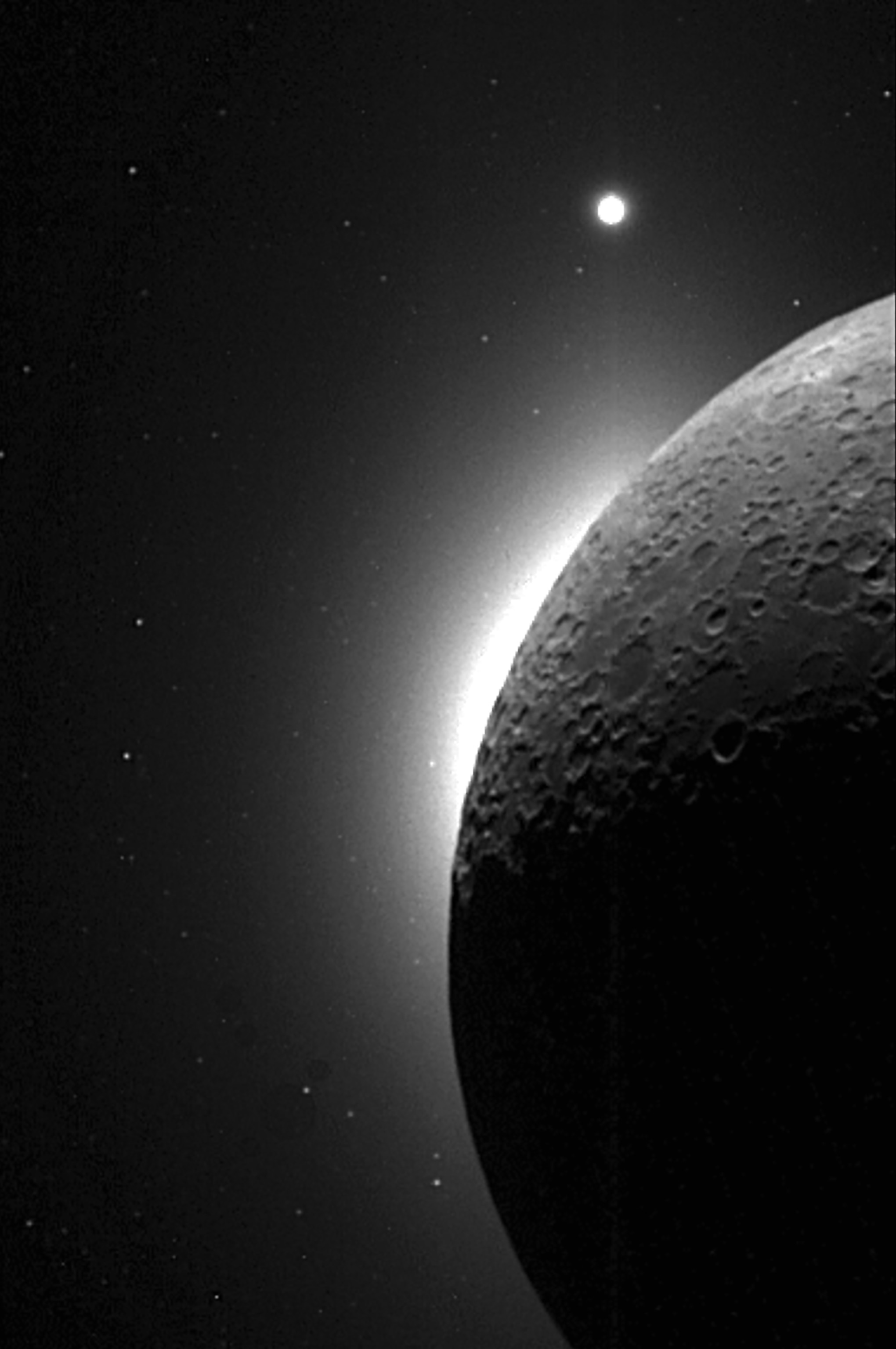 A light illuminates the shape of the moon from behind silhouetting half of its surface.