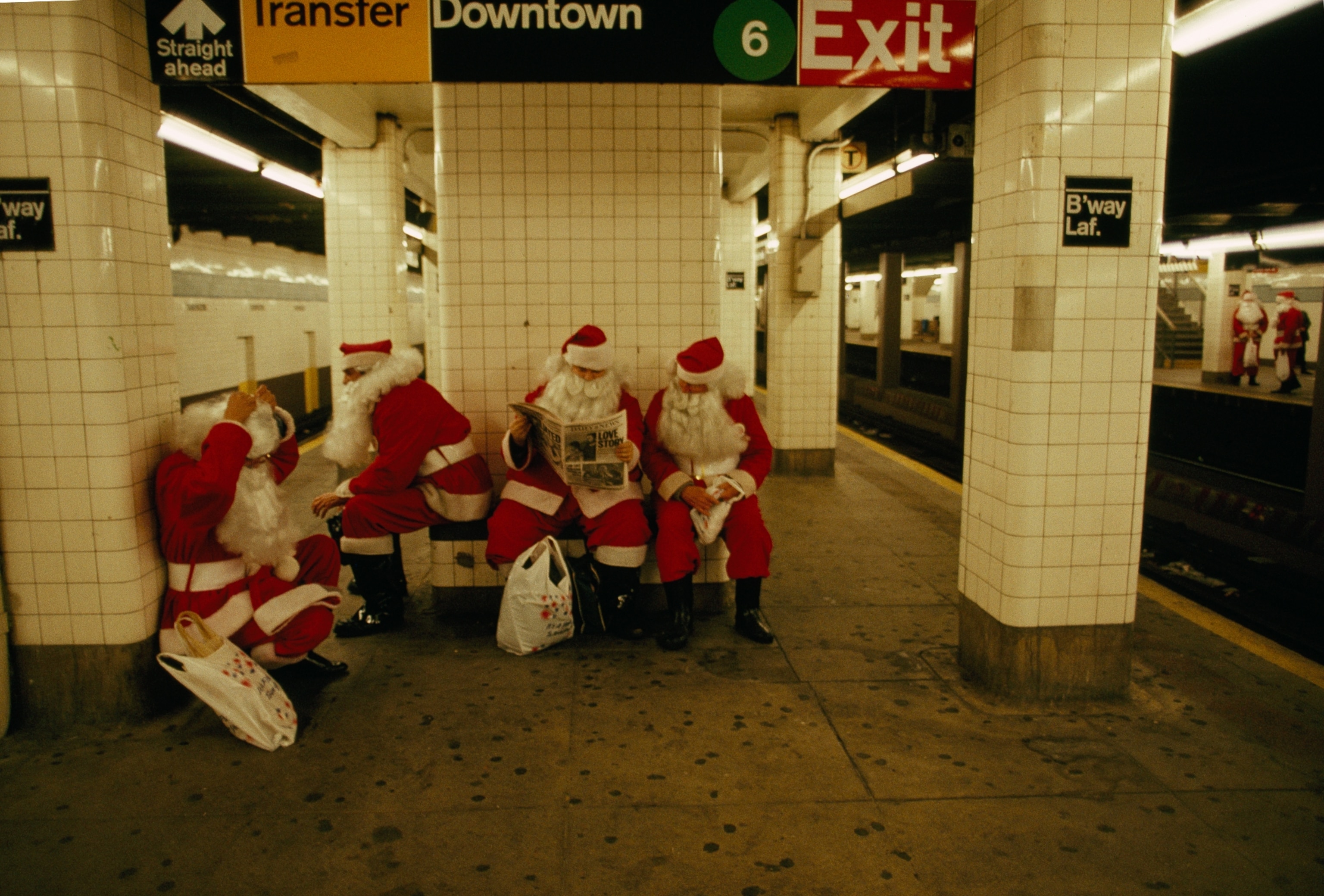 a group of Santa Clauses waiting for the train in the New York City subway station