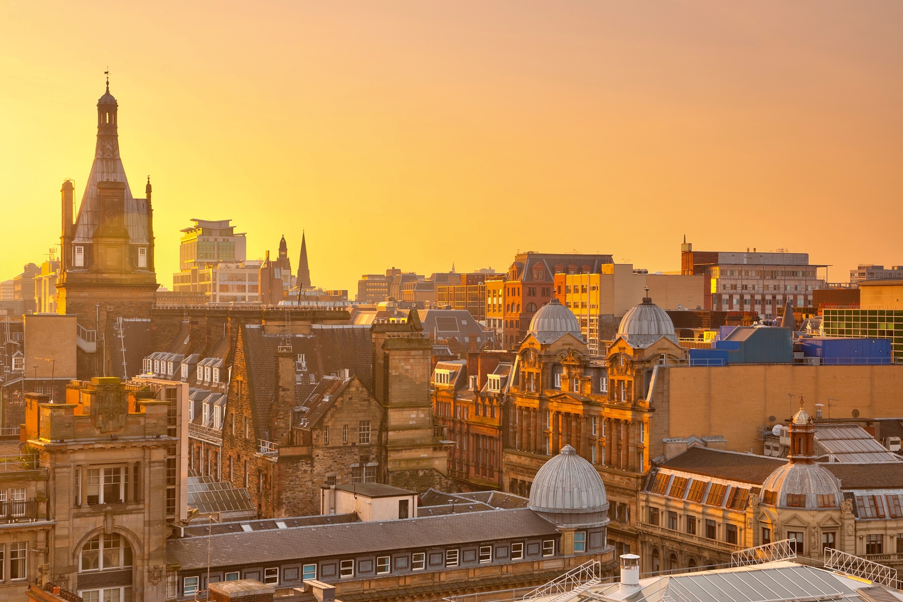 A birds' eye perspective on the partly domed, brick houses of Glasgow during sunset.