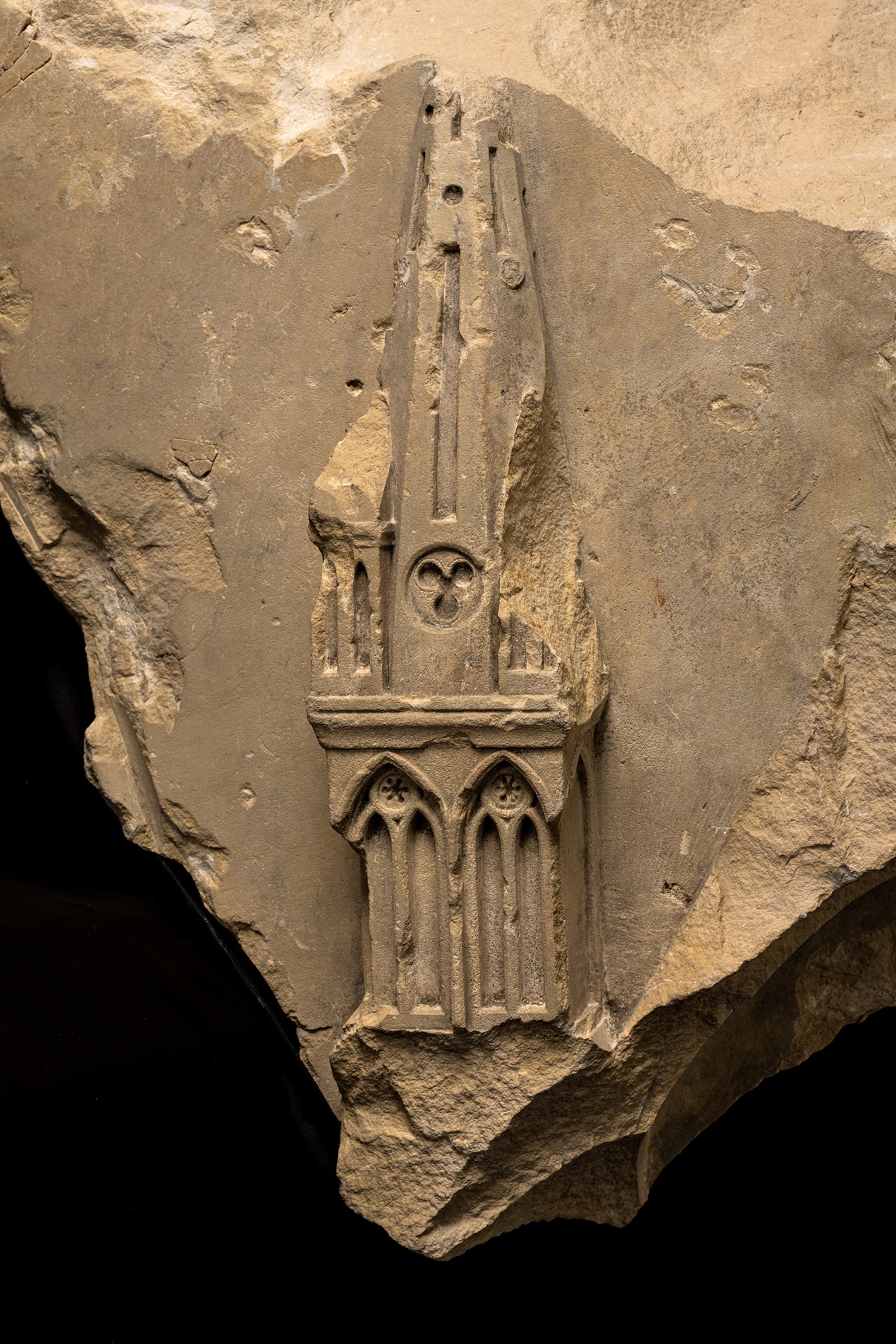 Sculpted decoration representing a spire of a religious building against a black studio background.