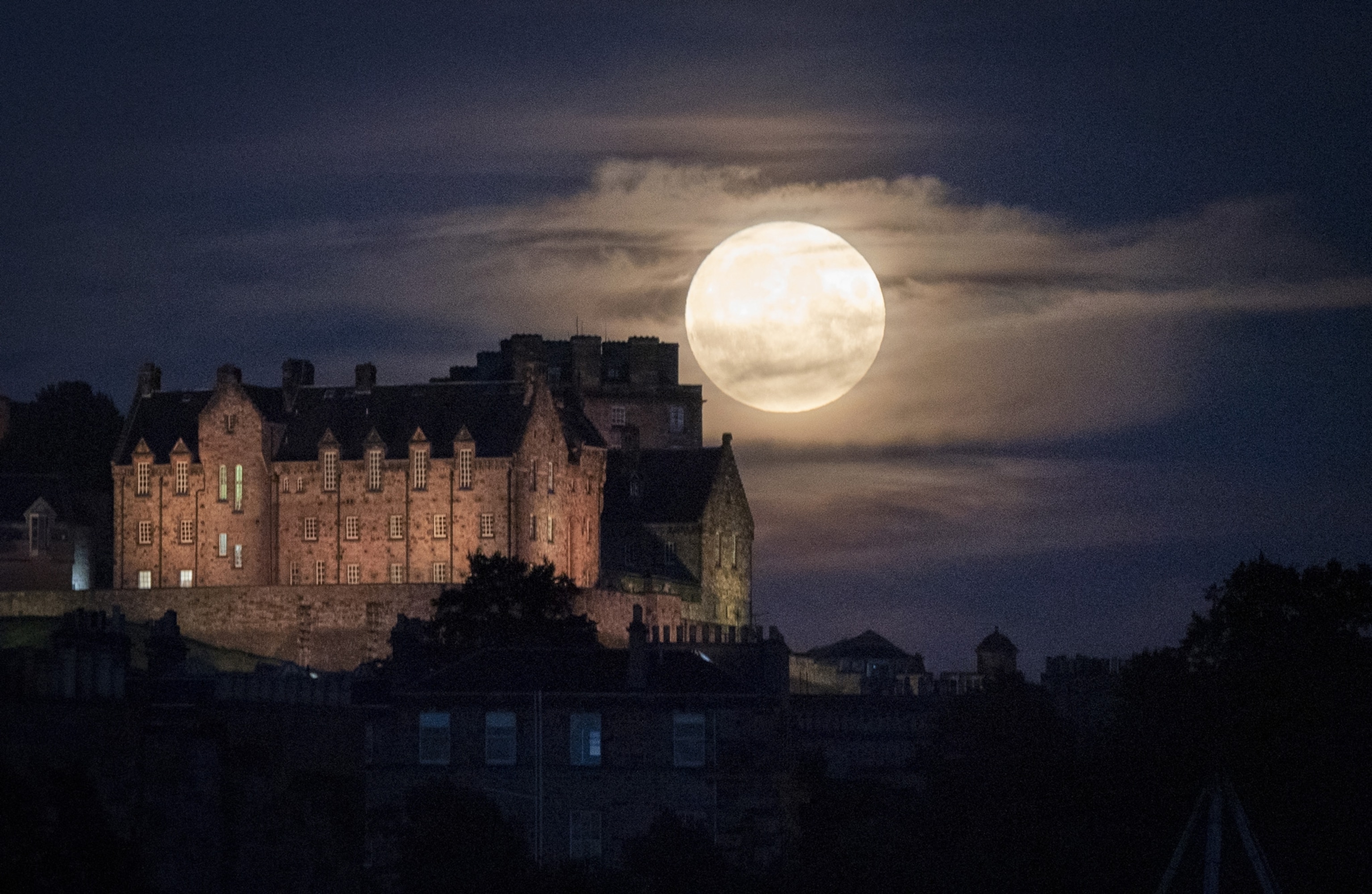 Photo of castle at night with large moon in background
