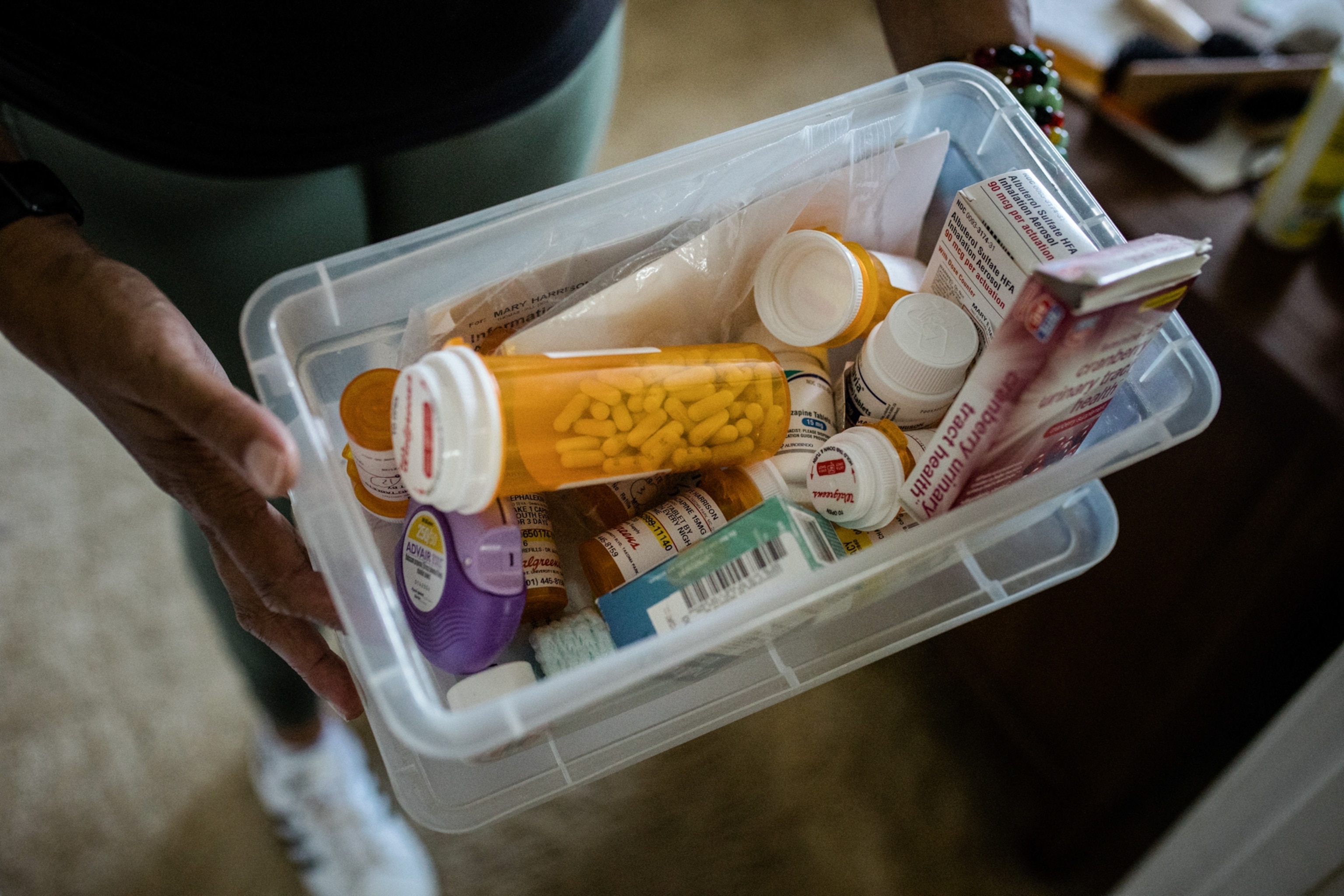 A small plastic bin full of various bottles of pills.