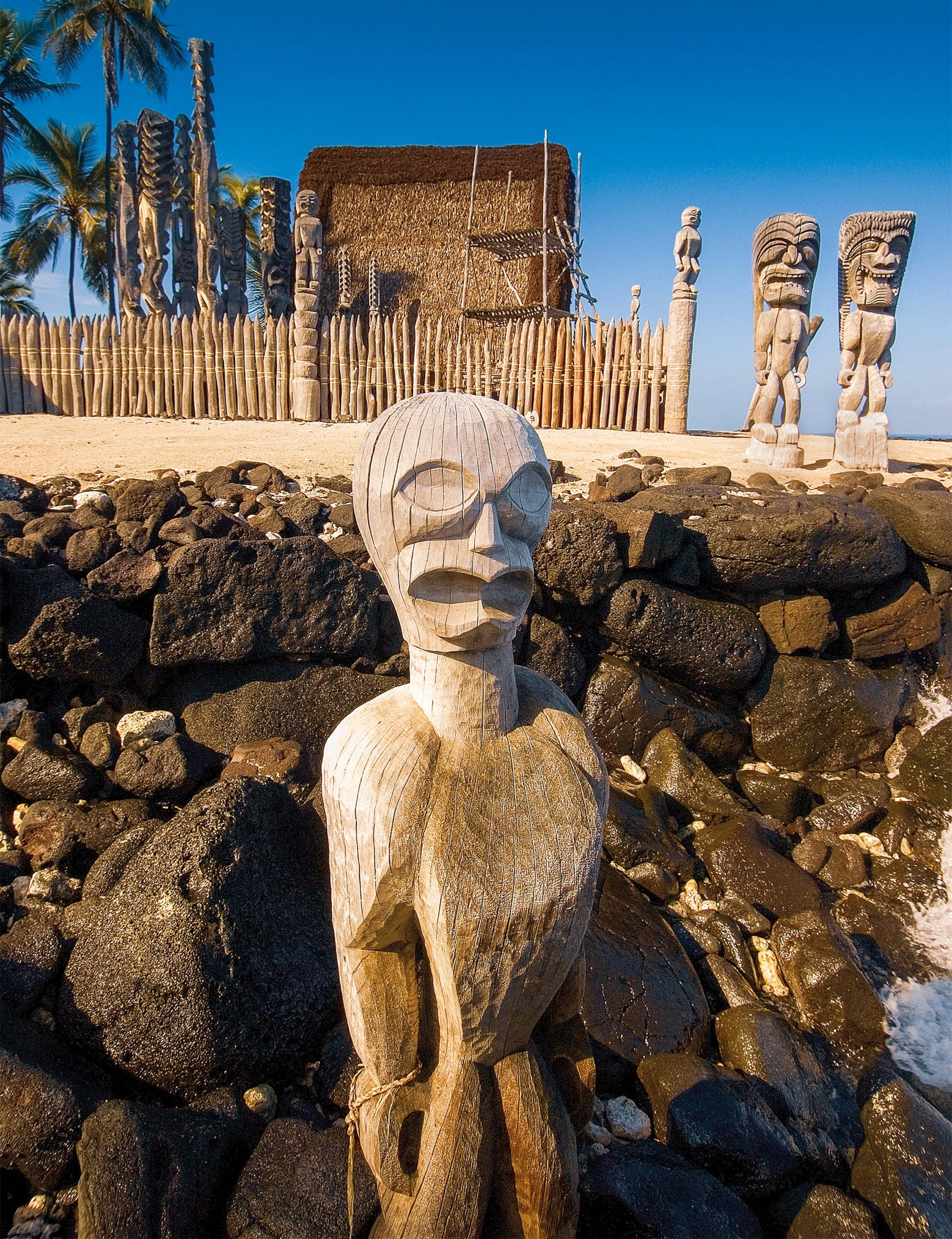 A wooden statue sits in rocks at the traditional resting place for Hawai‘i’s ancient kings