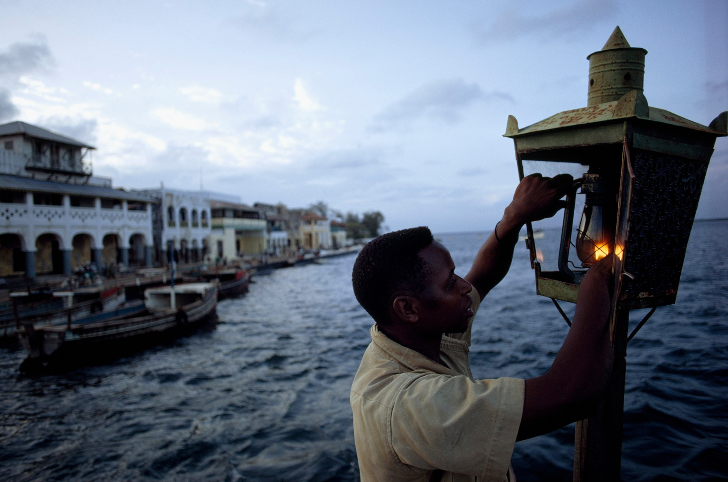 a man lighting a lamp to help guide fishing boats