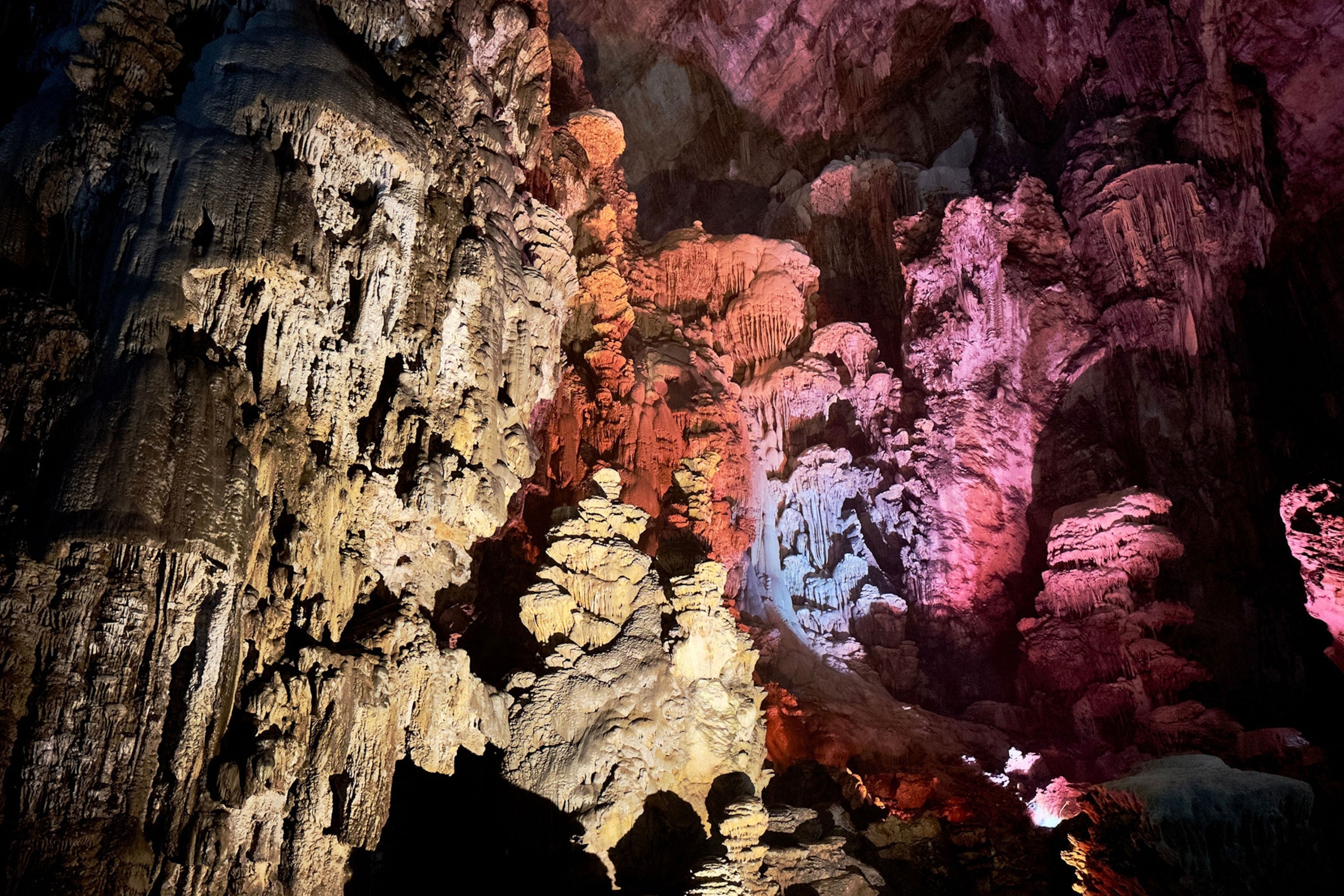 The inside of a cave with purple and pink and red lights.