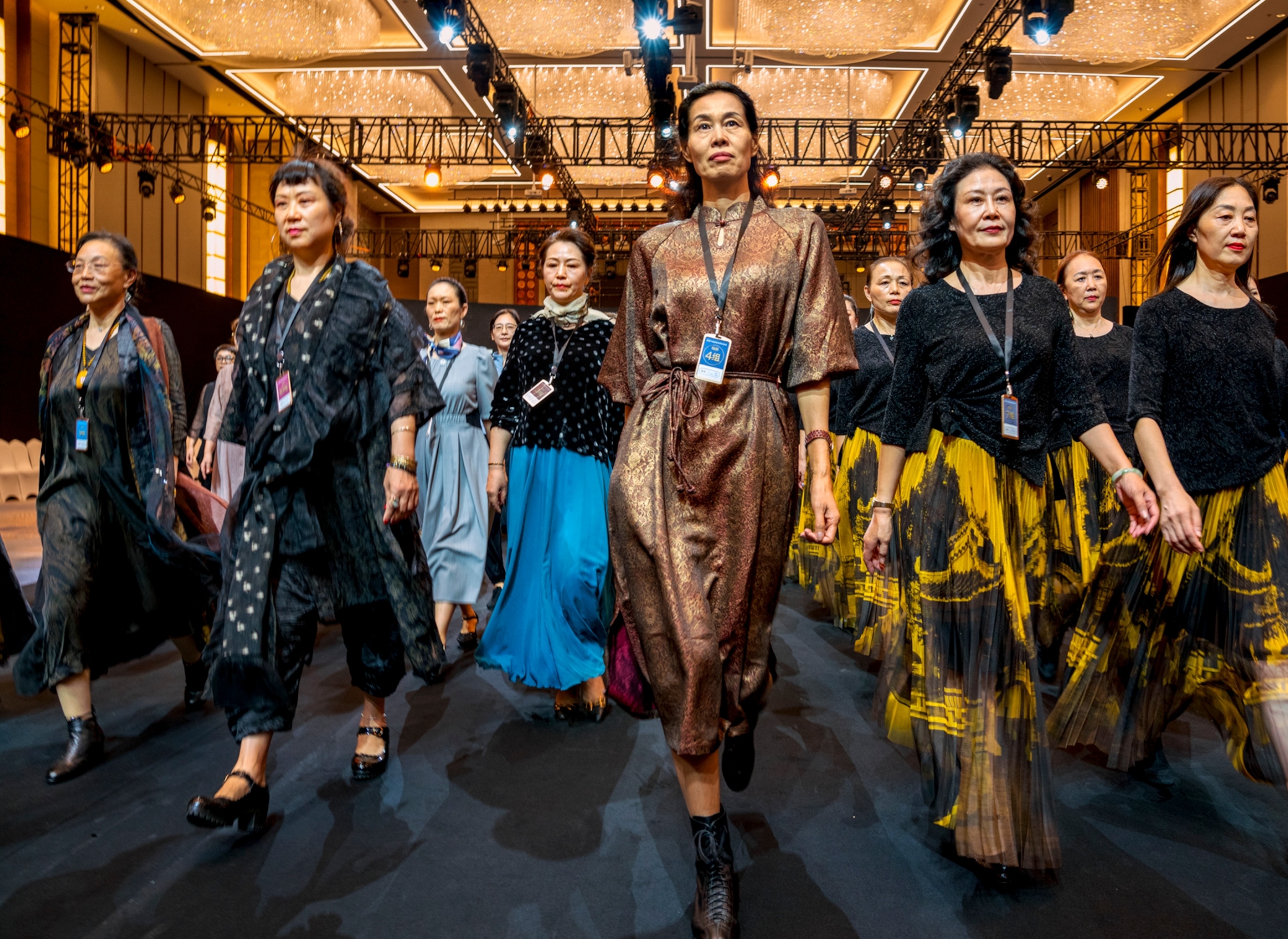 Picture of a group of women evenly spaced out walking in the same direction down a stage.