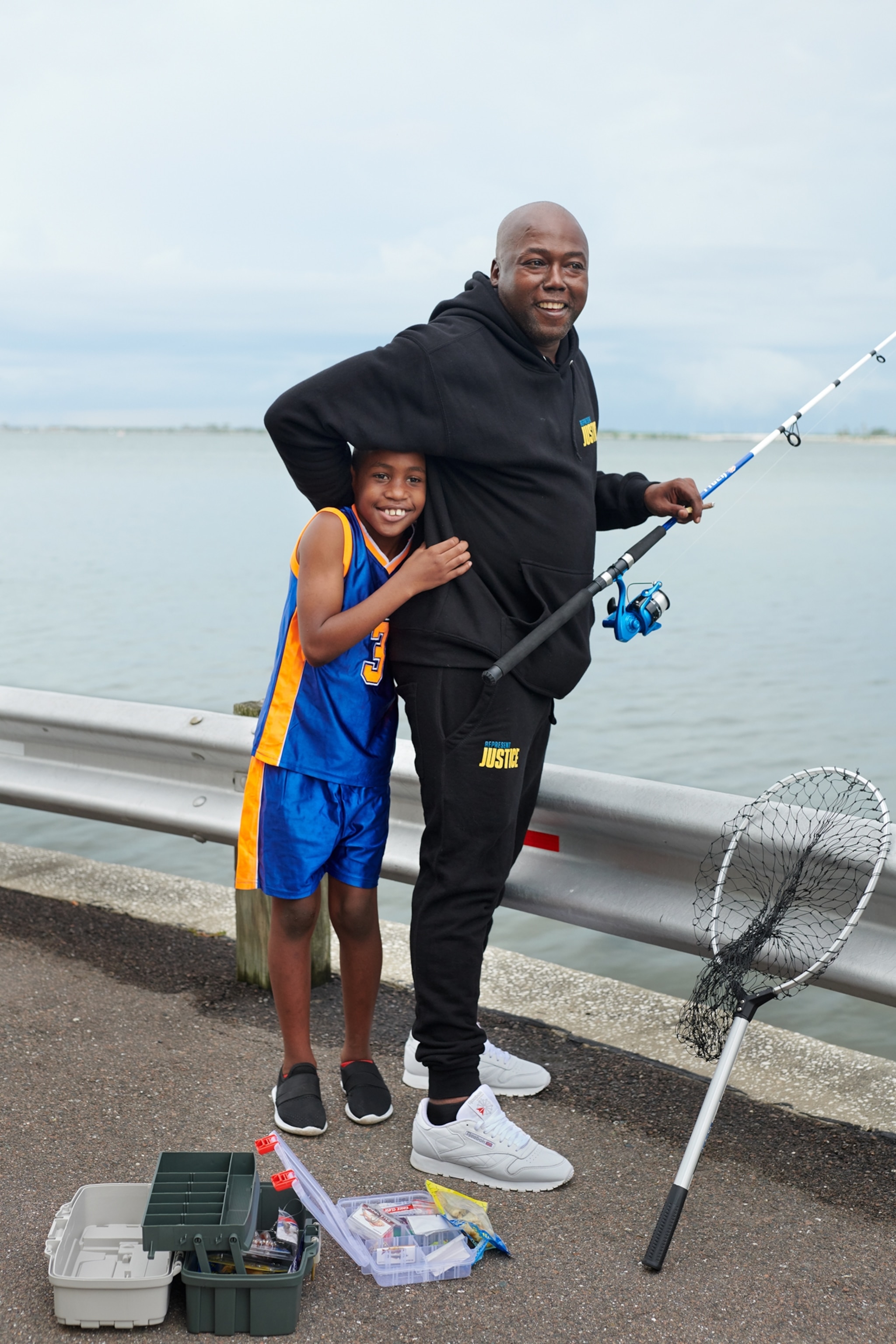 bald man with fishing rod and young boy embracing him.