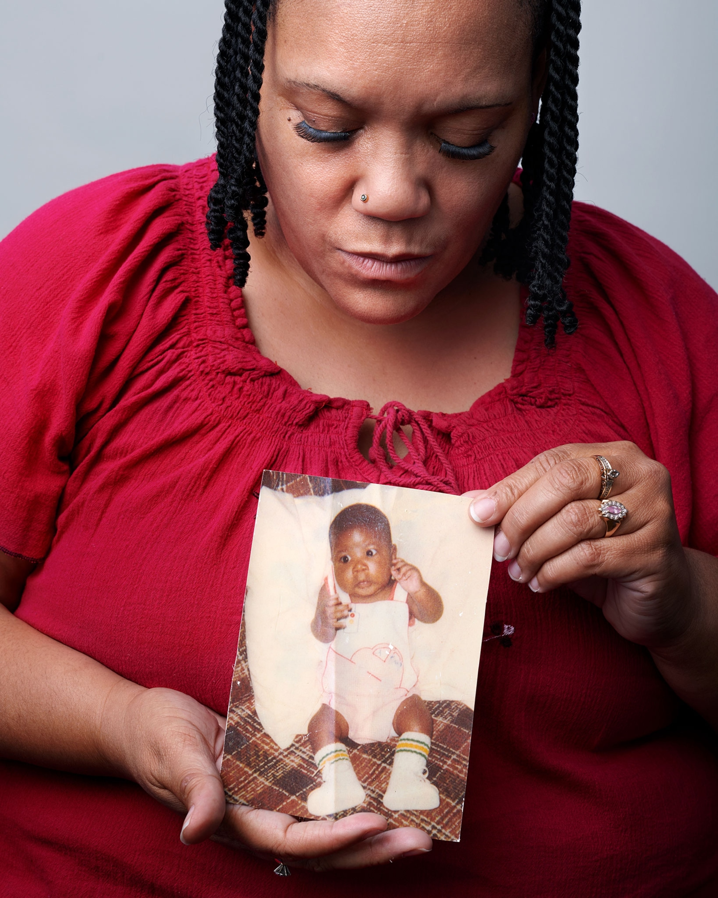 woman in red holding photograph of a baby.