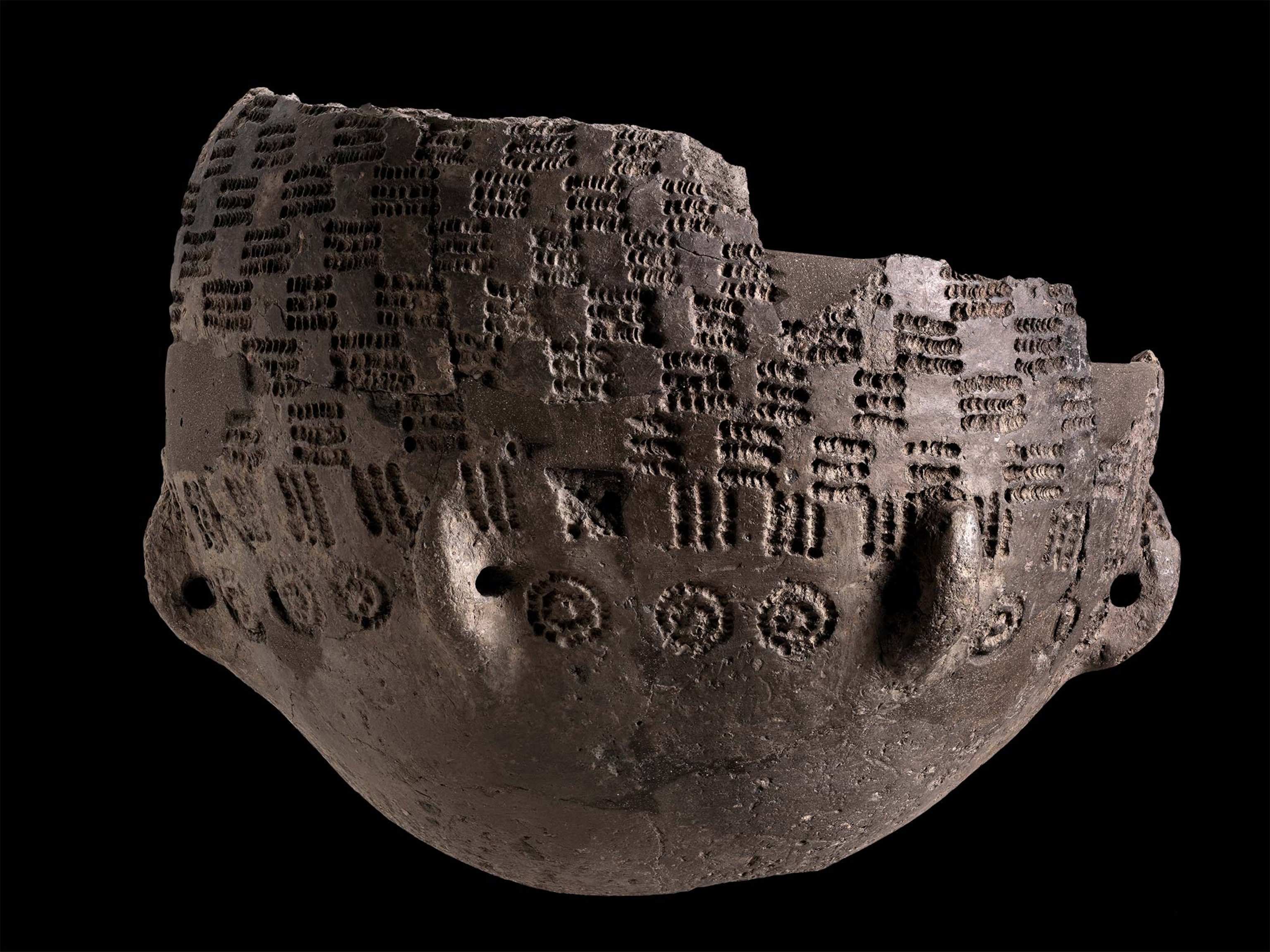 A decorate ceramic vessel in front of a black background