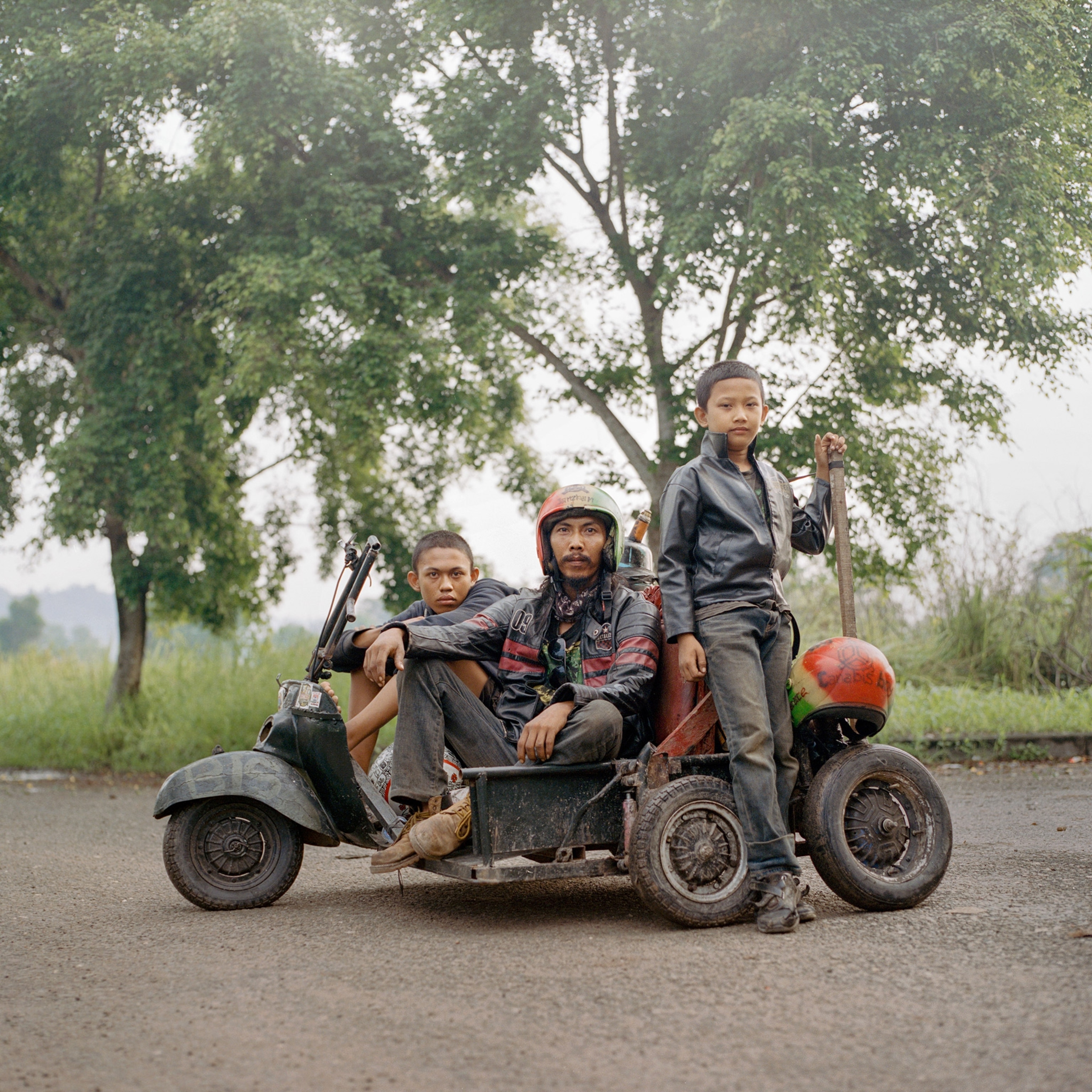 a man on his vespa with his son and a travel companion in Indonesia