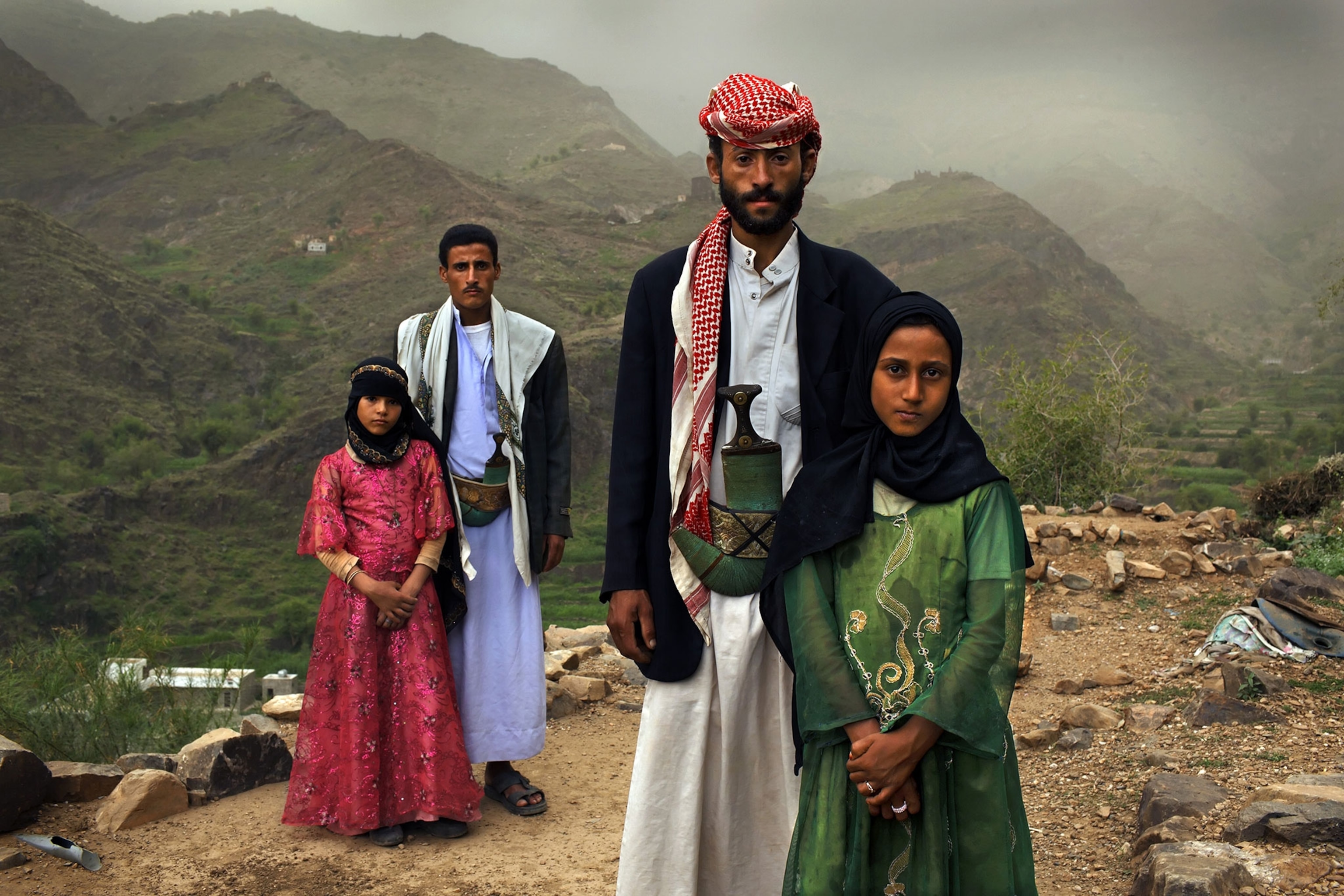 two very young child brides pose with their much older husbands in Yemen