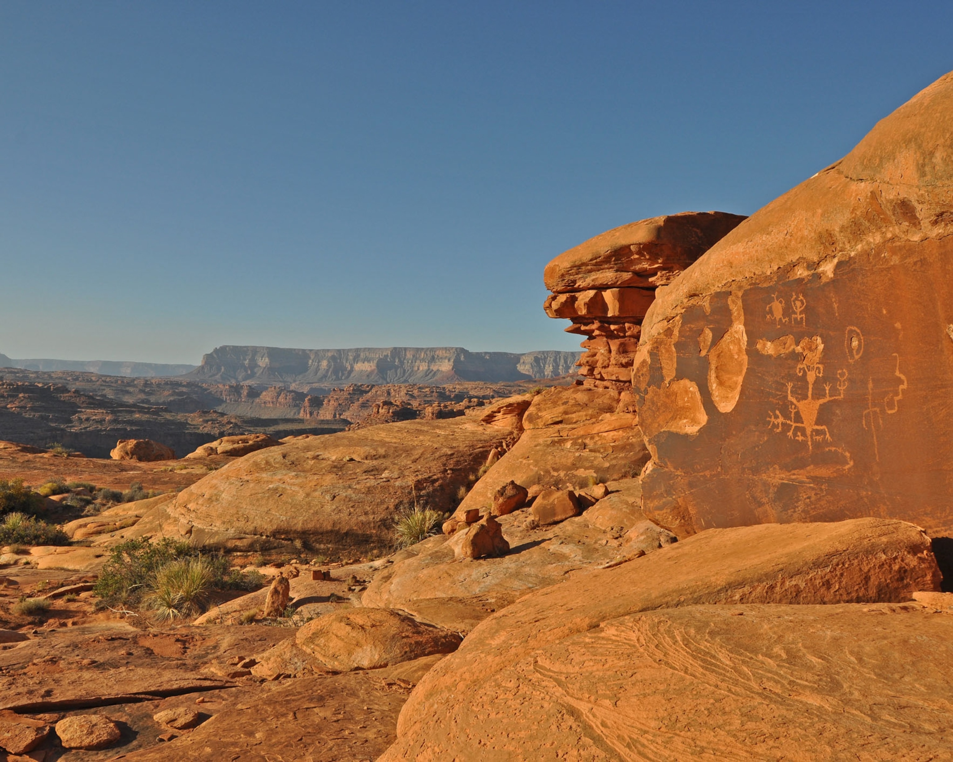Rock art carved into orange stone among the rocky canyon terrain.