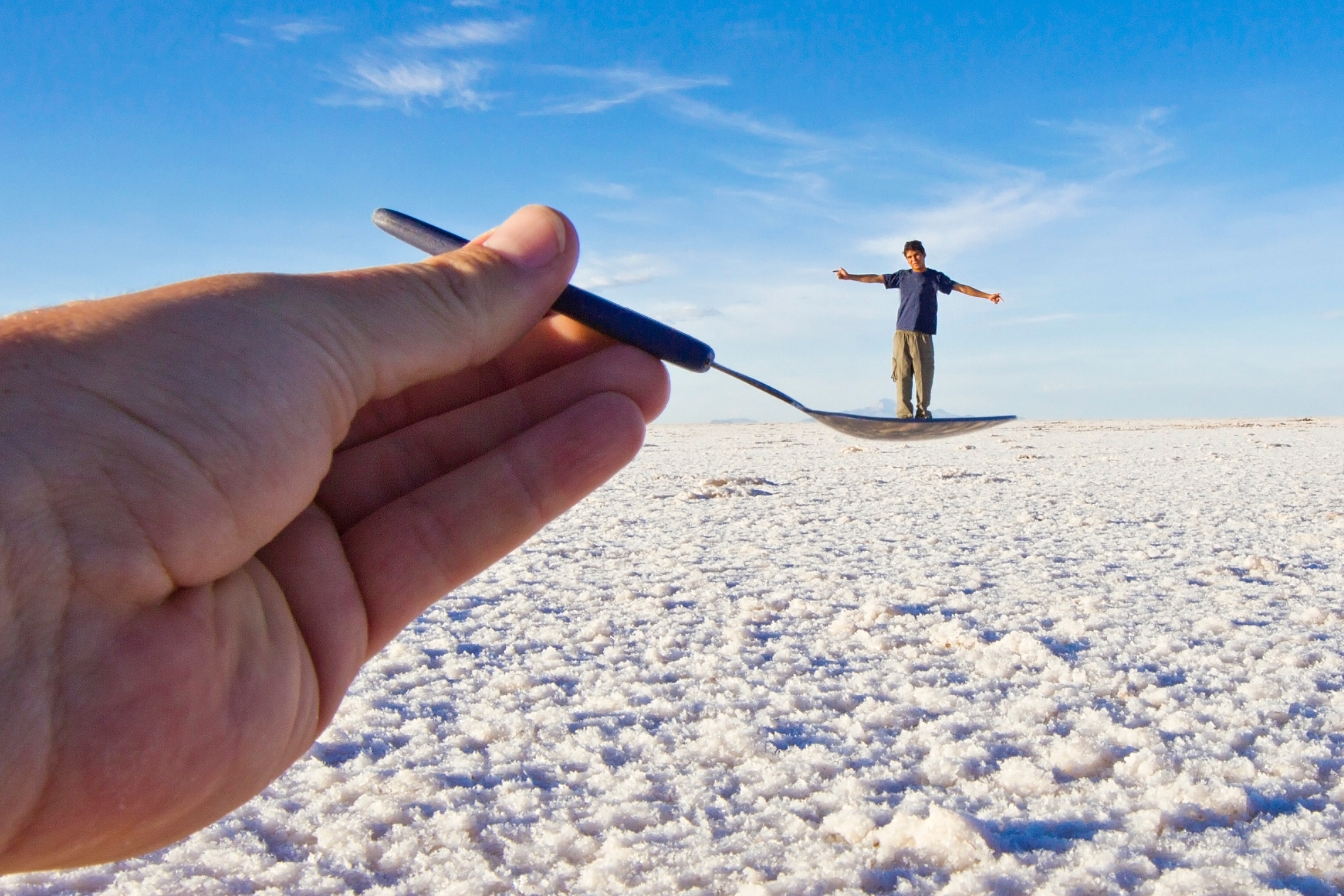 a man who appears to stand in a spoon at Salar de Uyuni, Bolivia