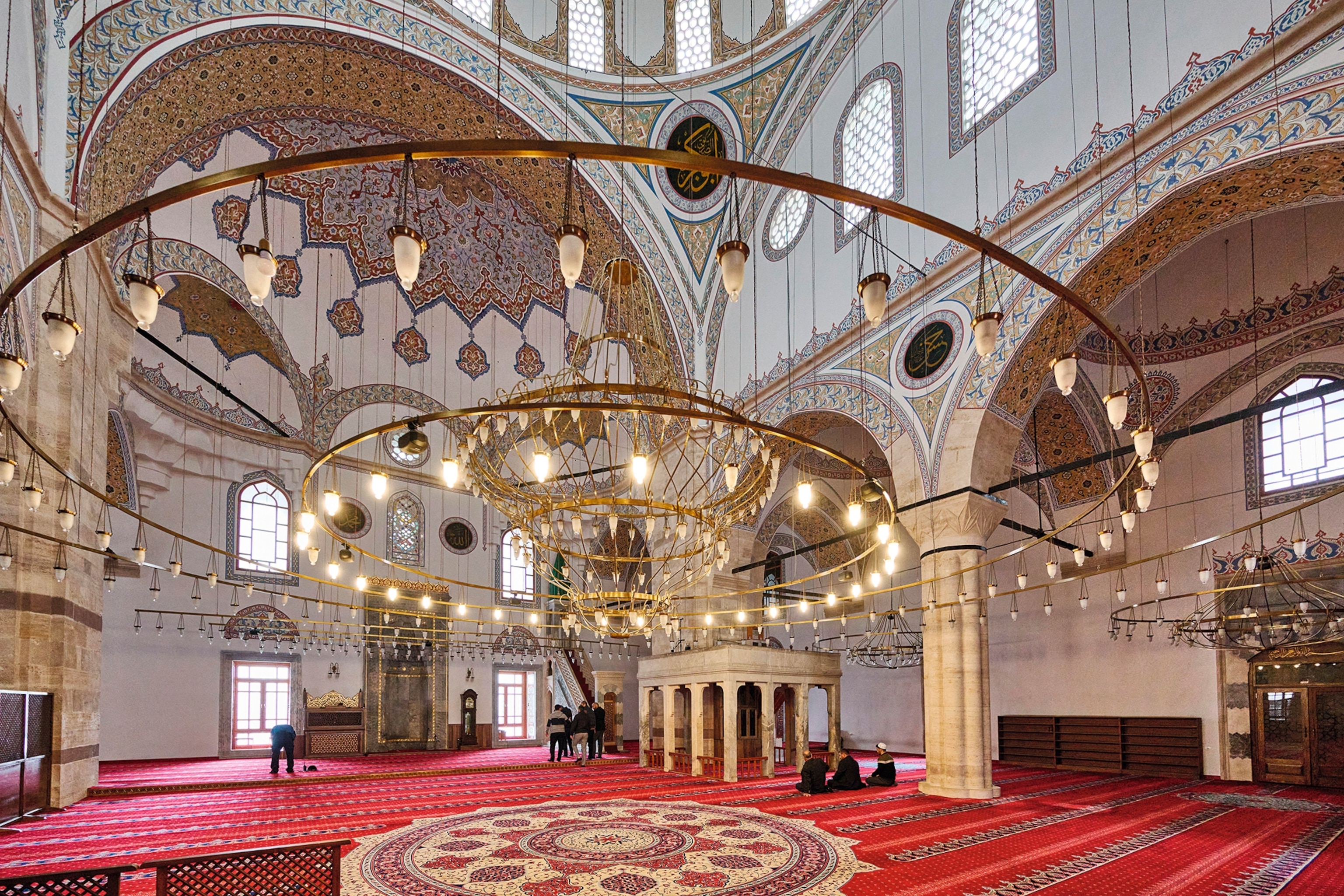 Interior of a mosque with hanging lights and mosaic tiled ceilings