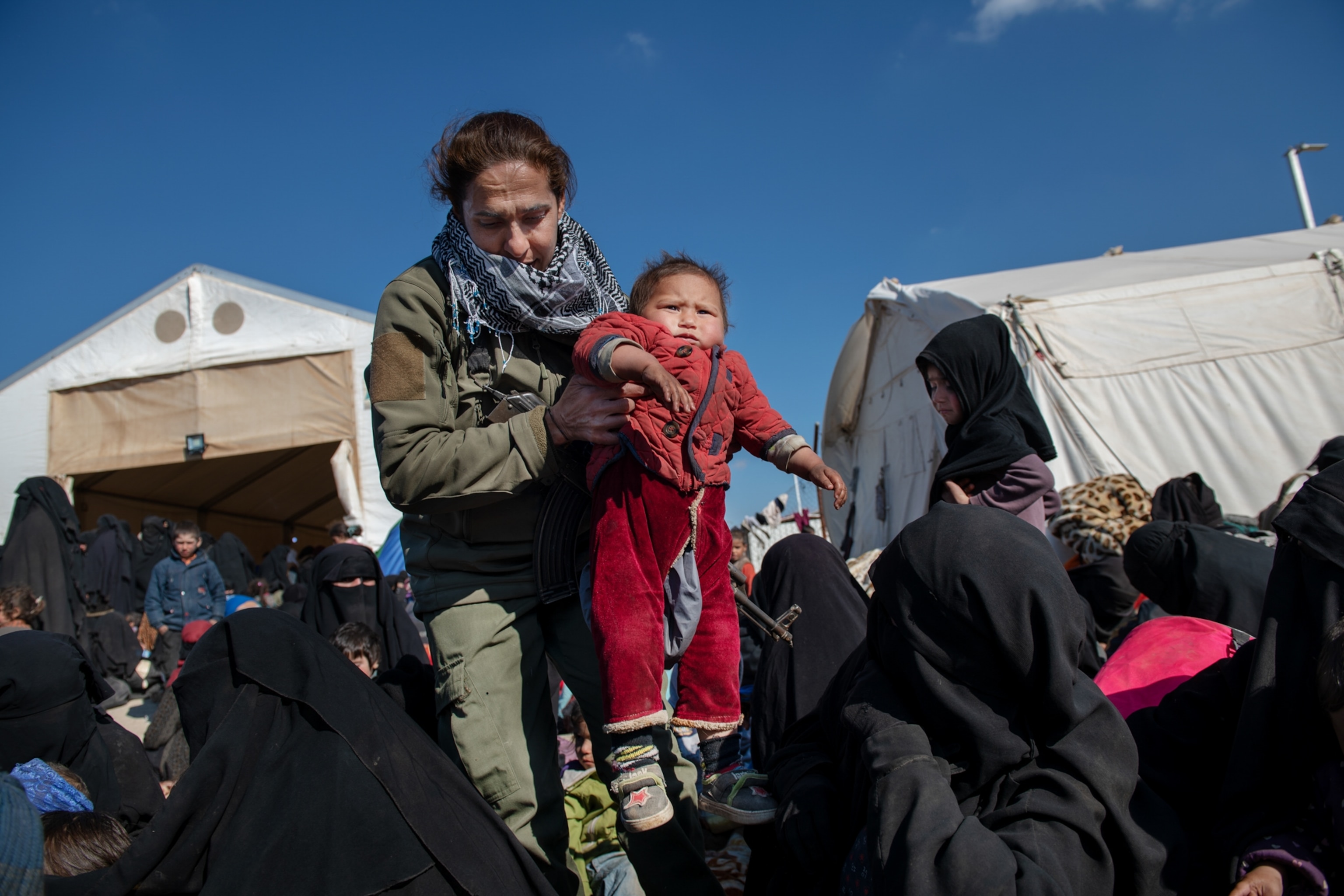 a woman carrying a child through a crowd