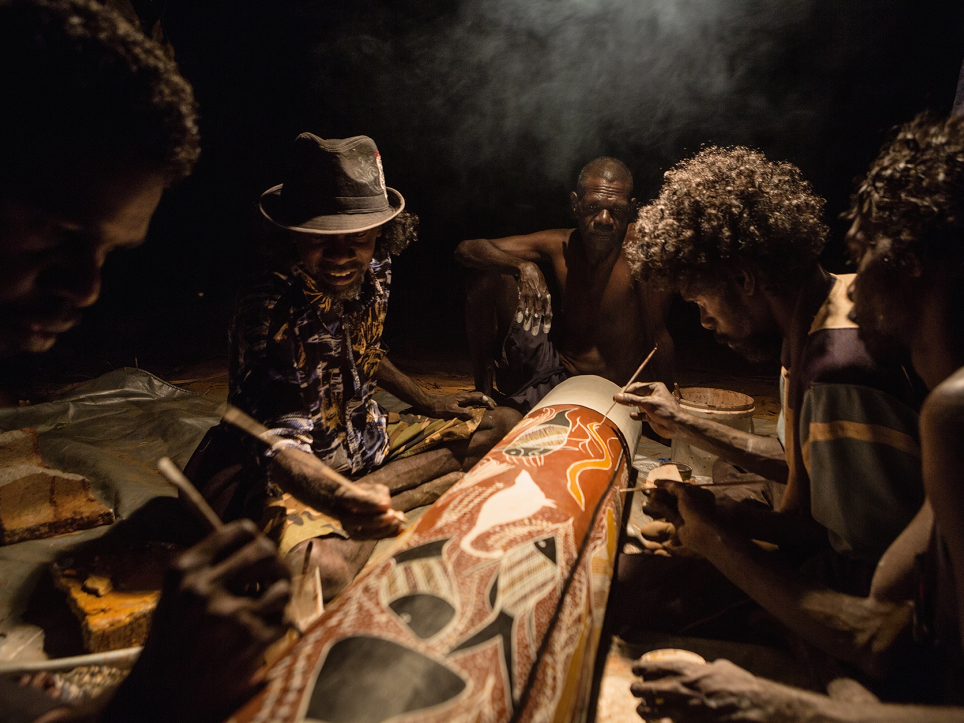 men decorating a log coffin in Maningrida