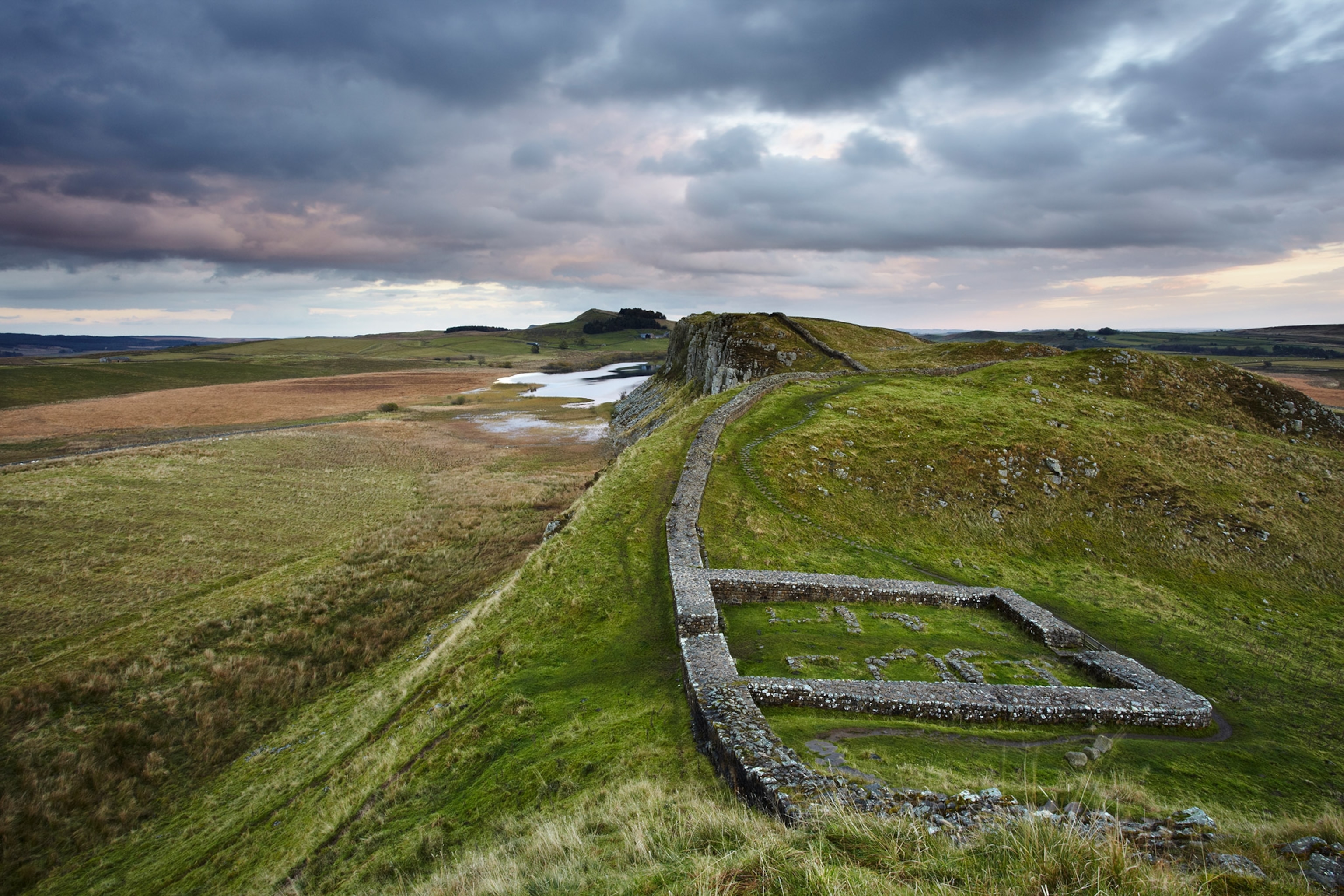 A view of Hadrian's wall and Mile Castle 39 stretching across the green landscape at dusk