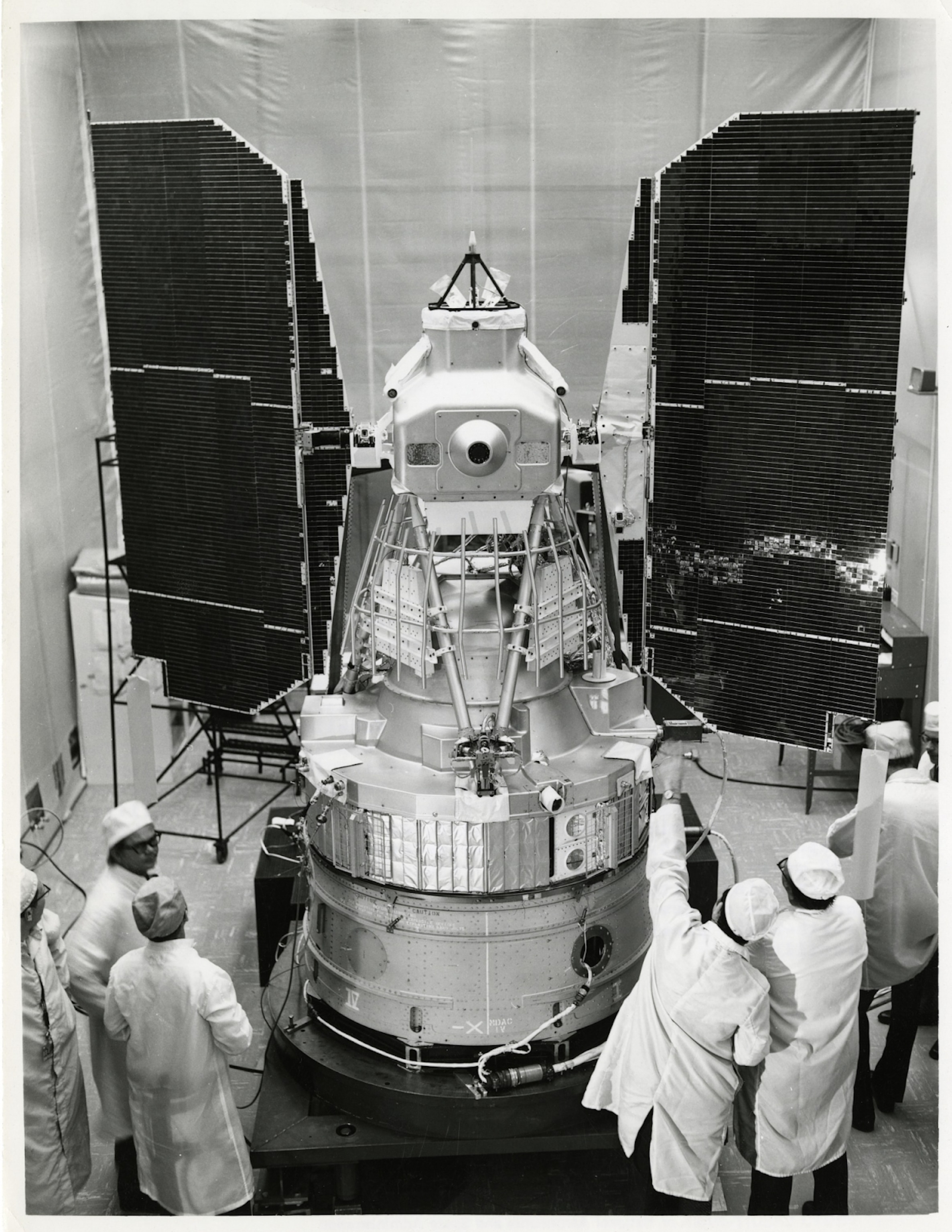 Picture of the Landsat 1 satellite in a clean room, surrounded by Landsat team members.