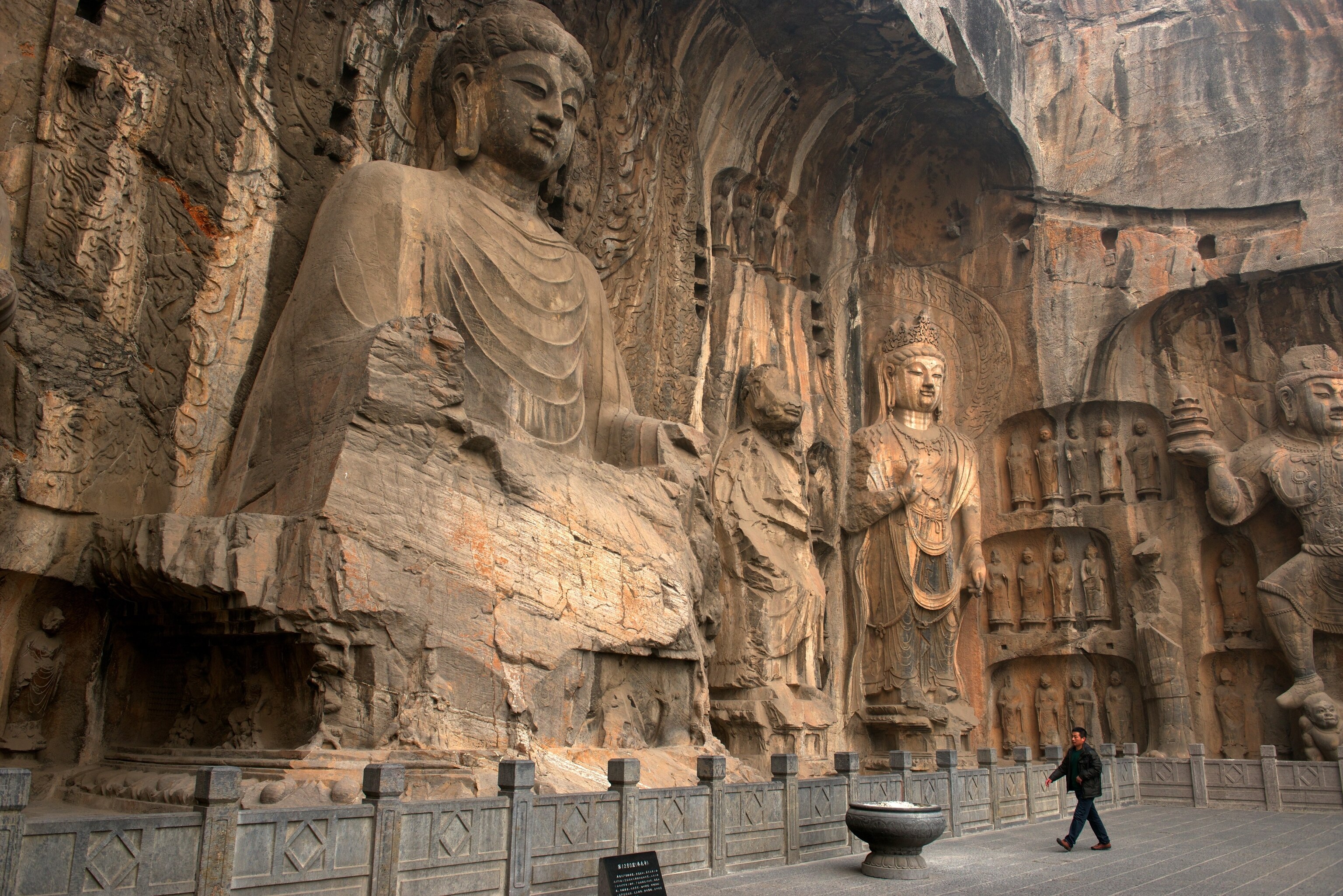 A tourist walks past the Longmen Grottoes
