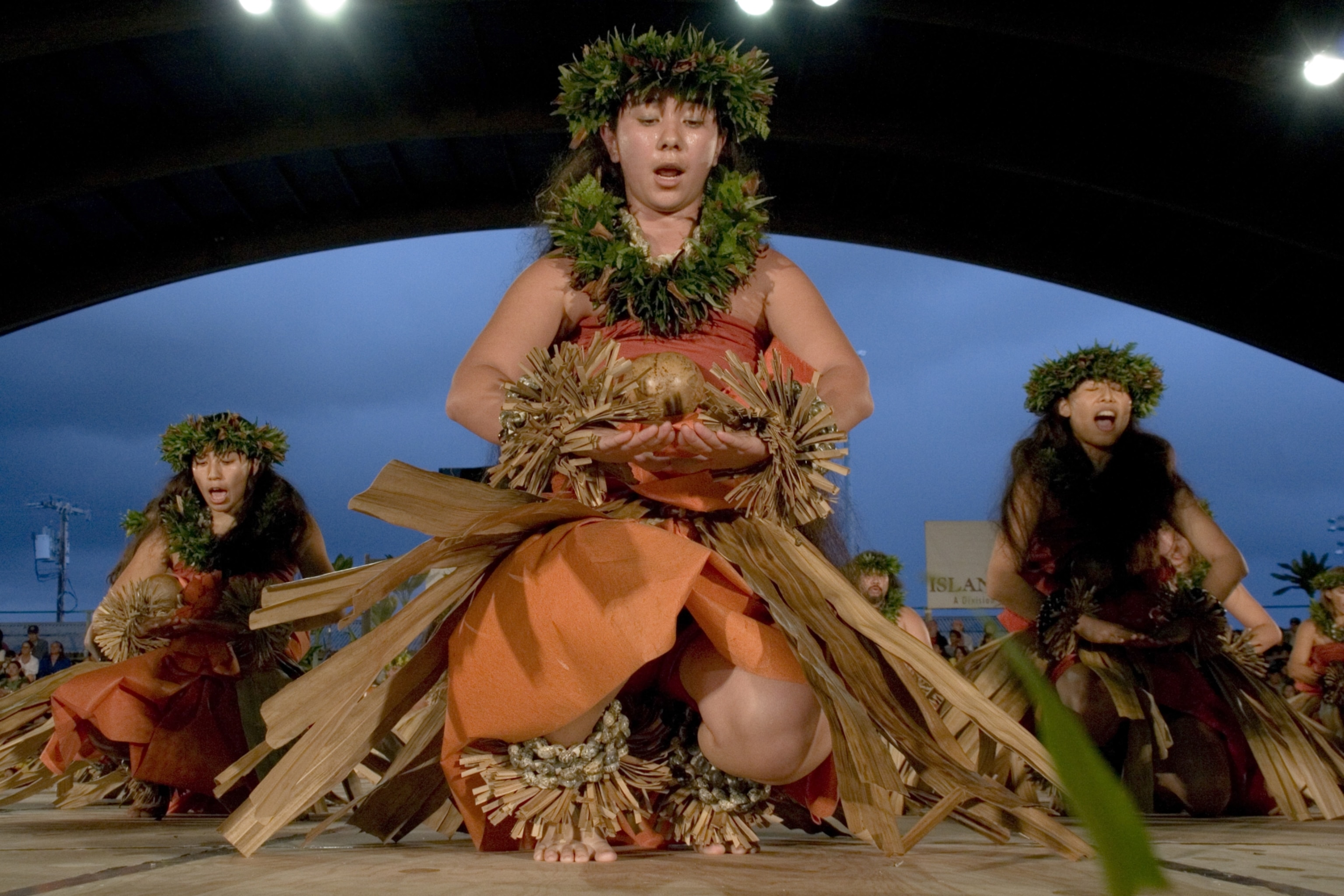 Women perform in traditional dances under stage lights during Merrie Monarch Hula festival