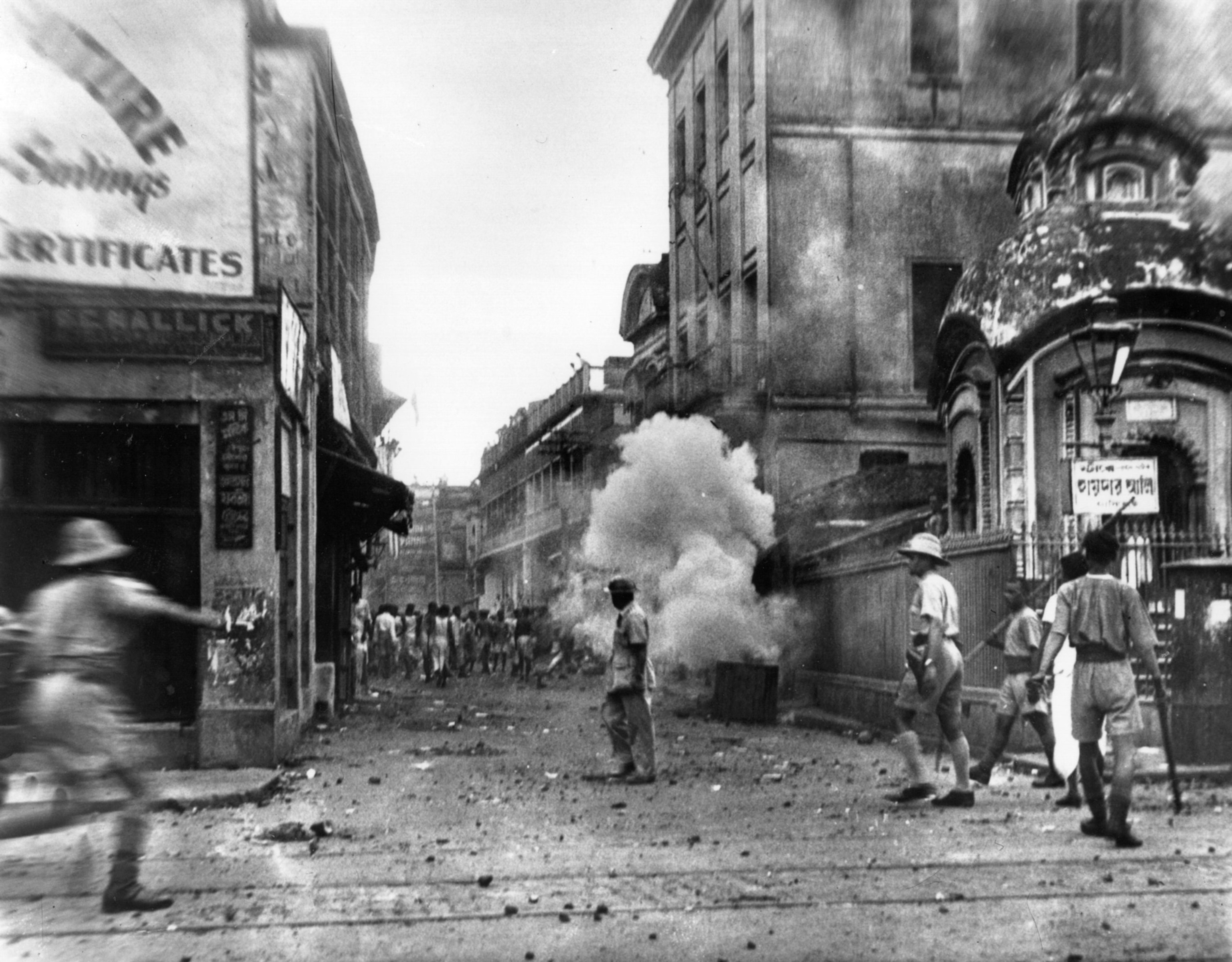 black and white photo of street with smoke and people running
