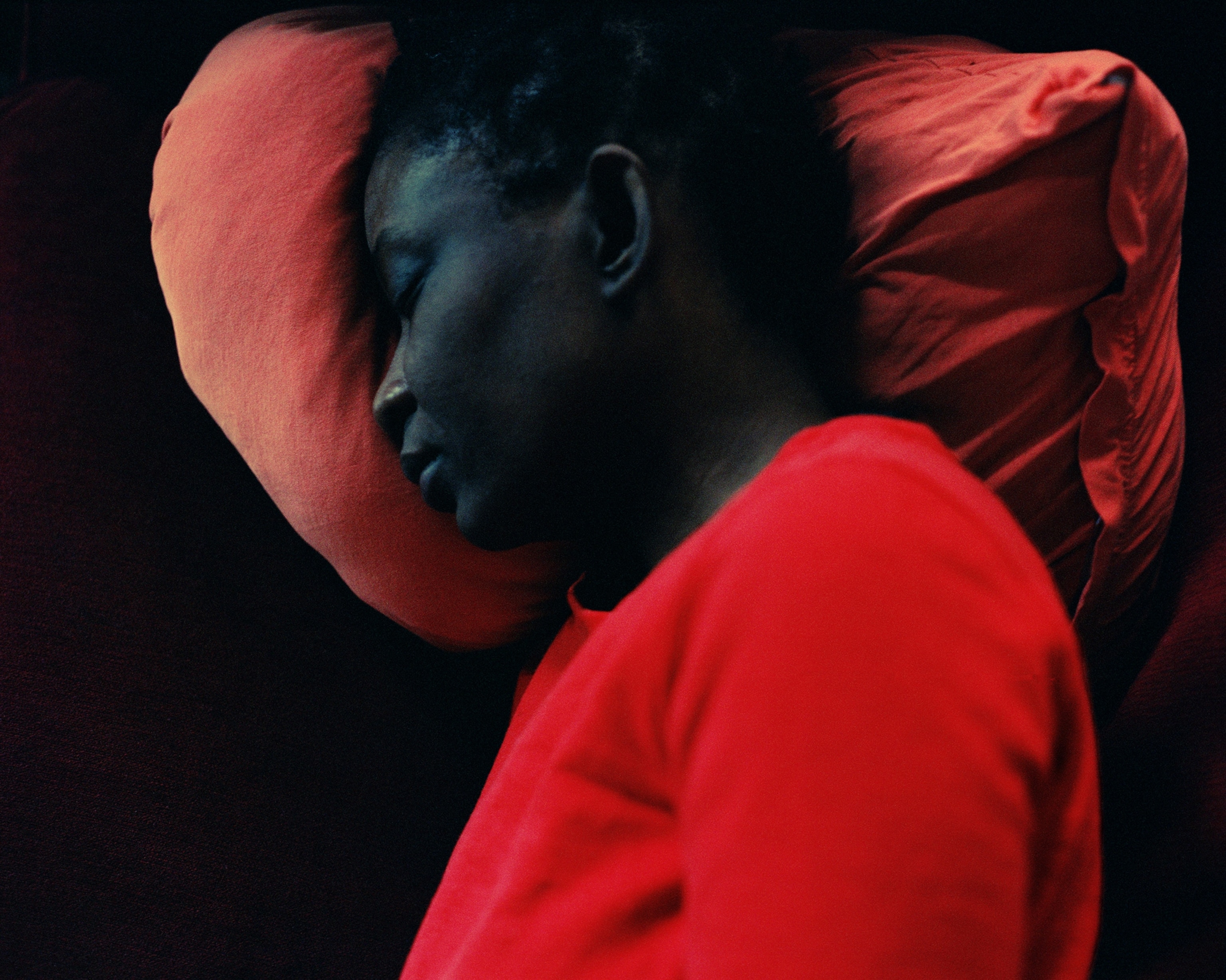 A person in a red shirt sleeps on a red pillow.