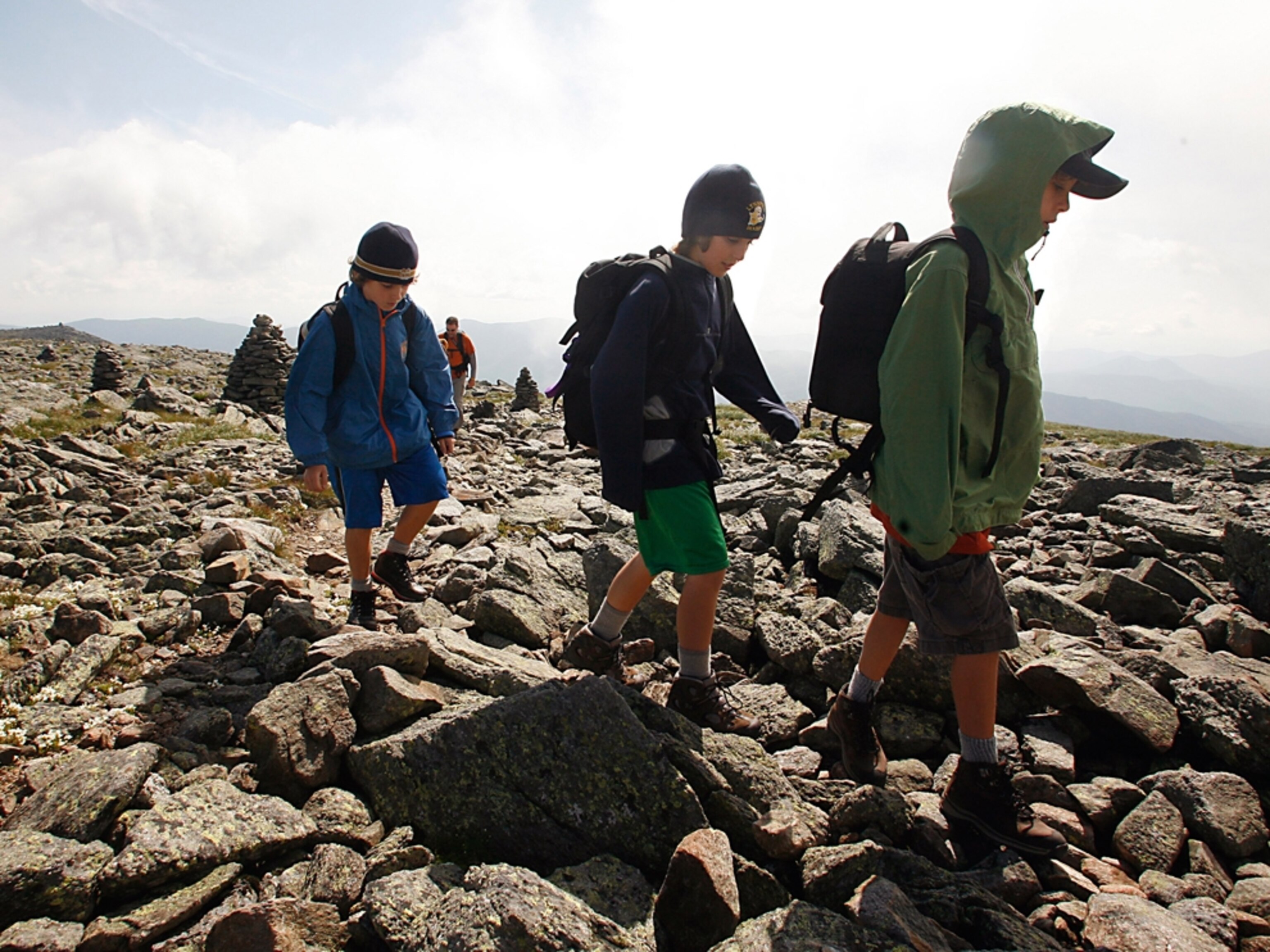 Boys hiking over rocky ground