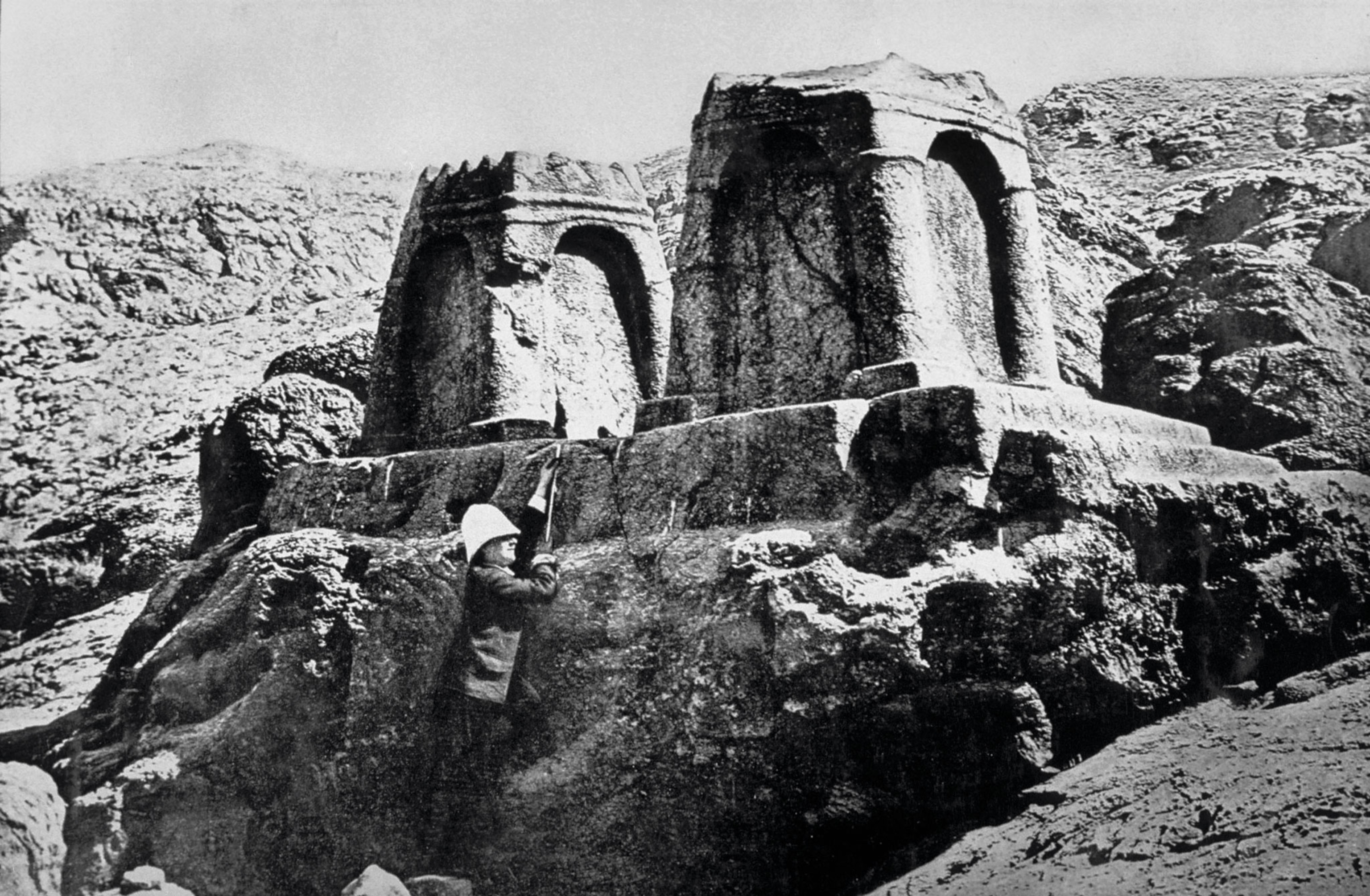A person measures a stone monument