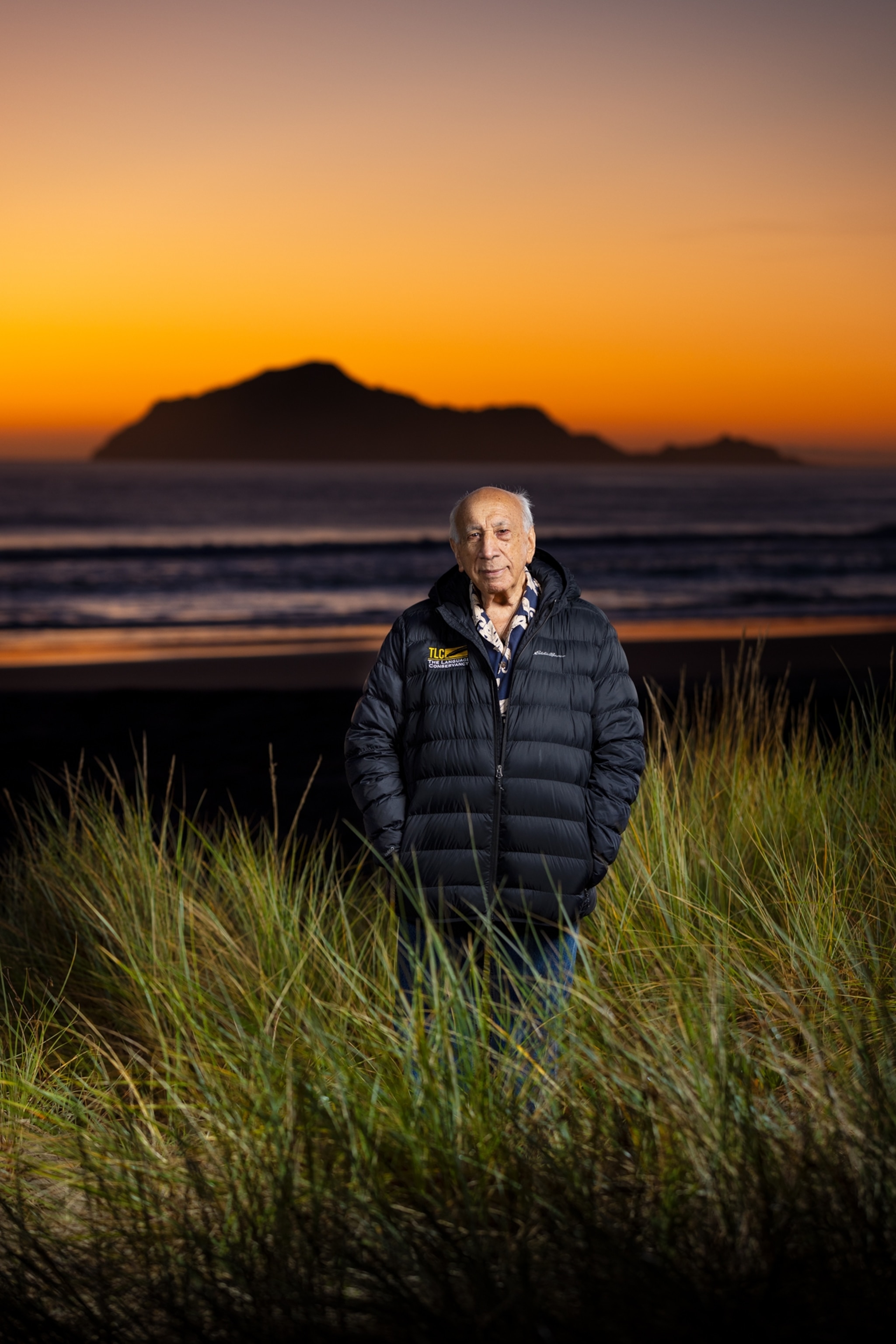Man standing with sunset over mountain on the background.