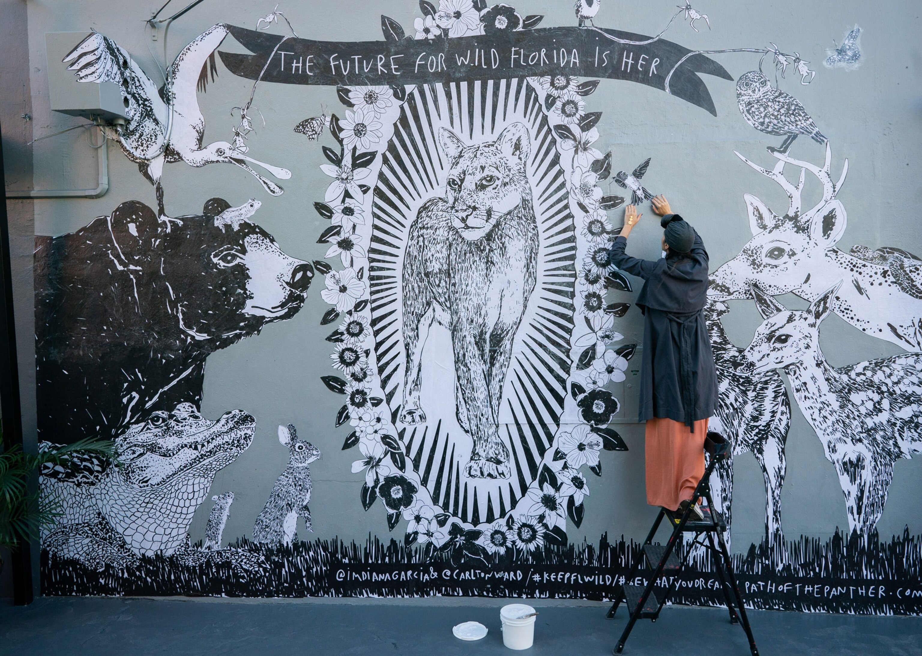 an artist paints a mural of a panther based off Carlton Ward Jr.'s photograph