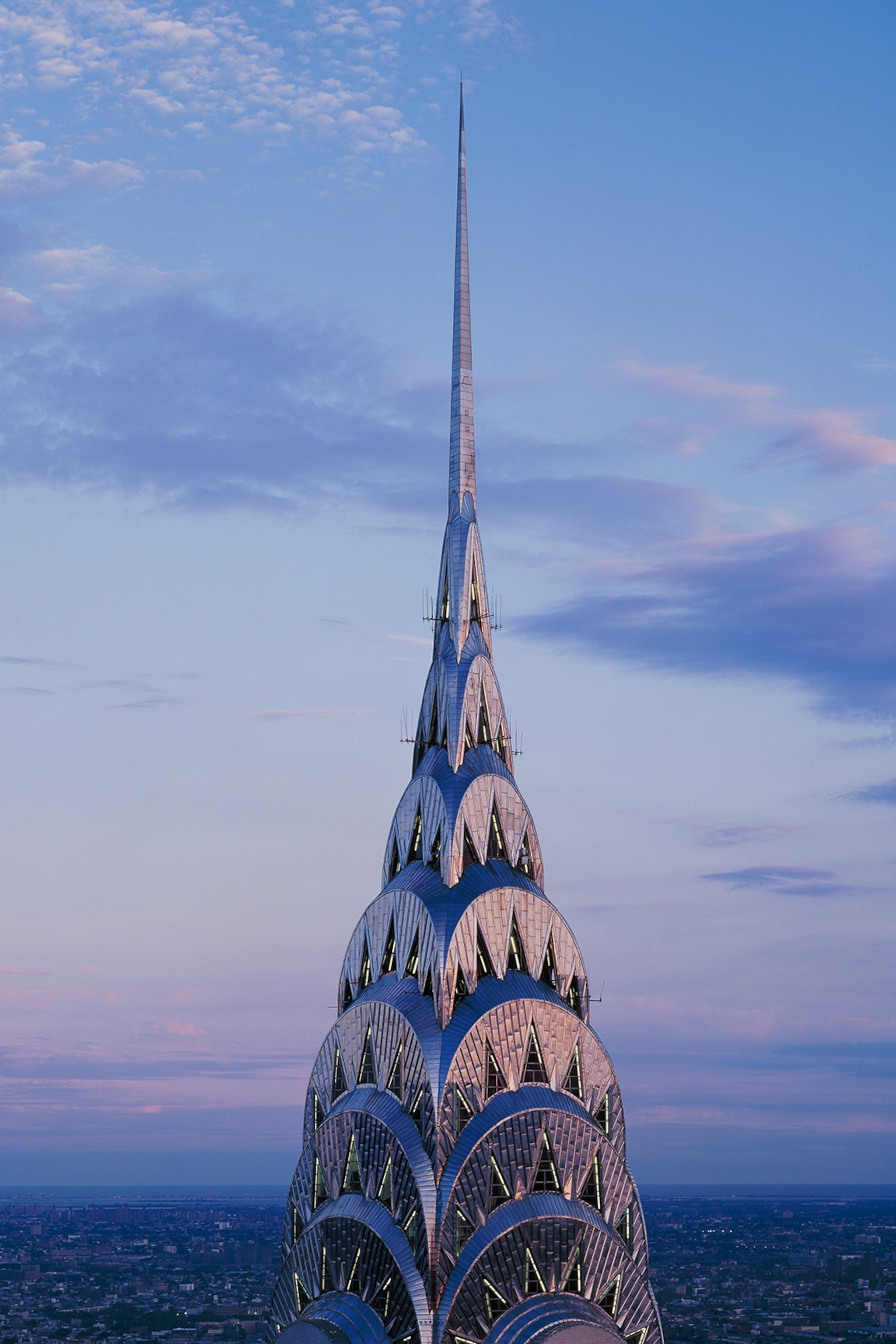 A close-up of the Chrysler building's scalloped spire against a twilit sky.
