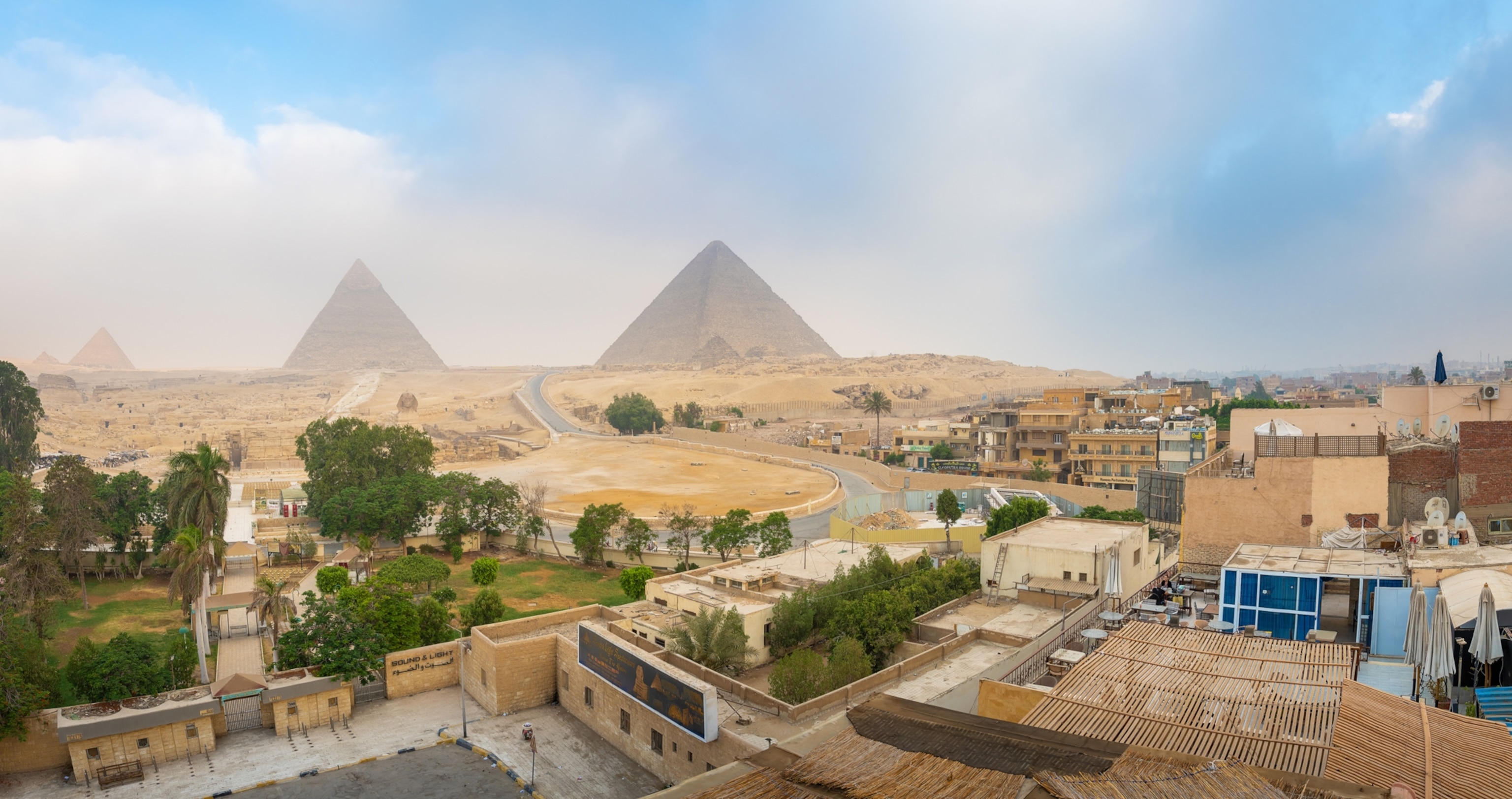 buildings and city roads sit at the feet of egyptian pyramids