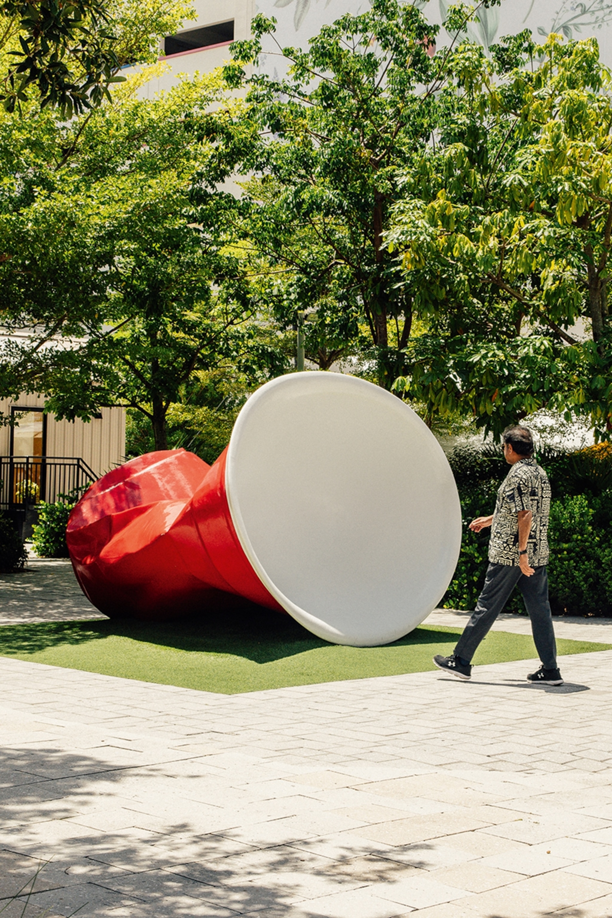 Man walks past a large art sculpture in a park