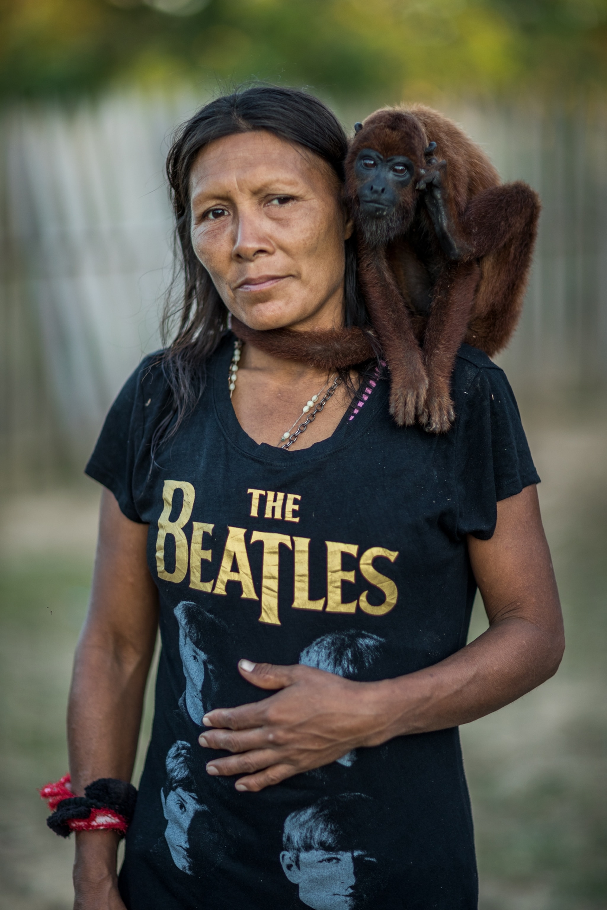 a woman wearing a Beatles shirt with a brown monkey on her shoulder