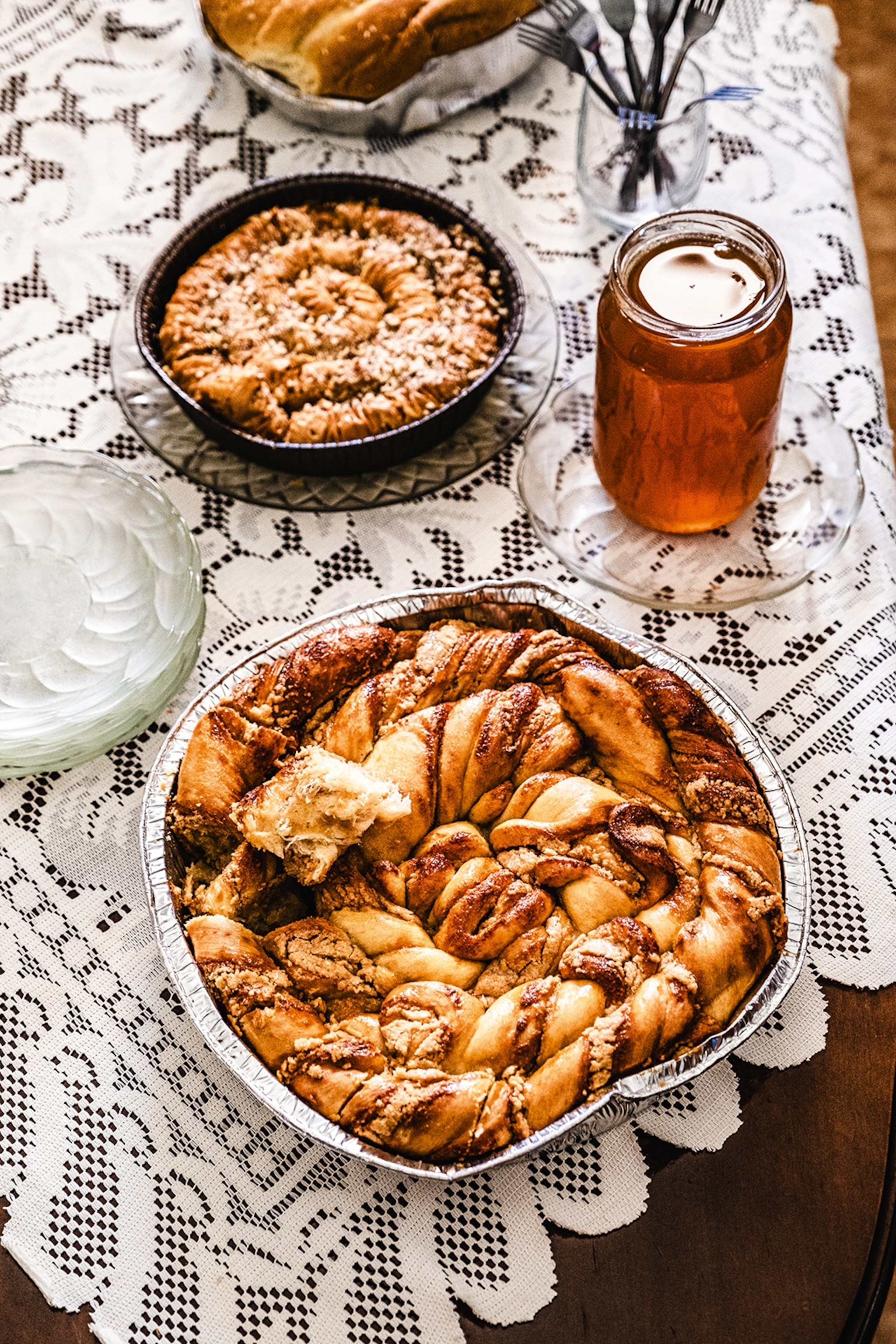Baked pastry in a tin foil container next to a jar filled with honey