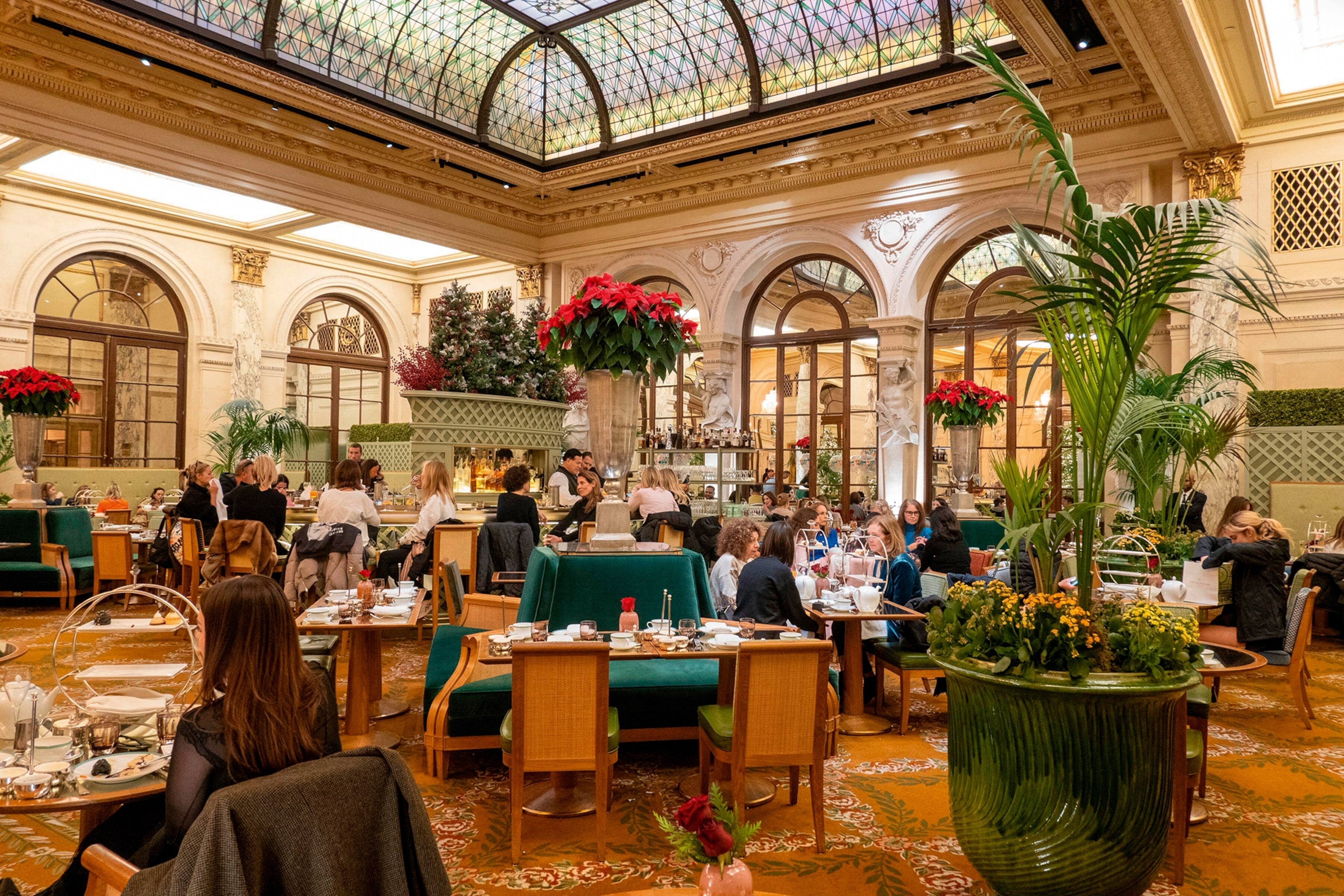 A dining room with a high, glass-domed ceiling and velvet seating islands.