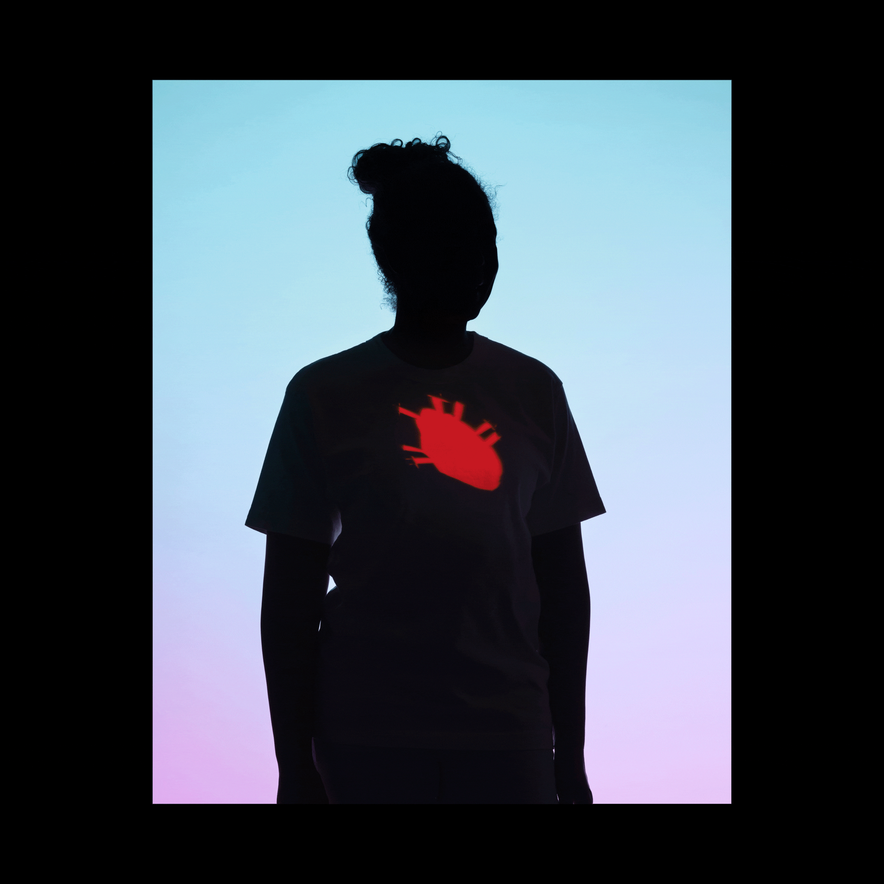 A woman silhouetted against a background that fade from light blue to light pink; projections of a heart, breasts, and ovaries cycle every second, appearing on the silhouetted woman's body
