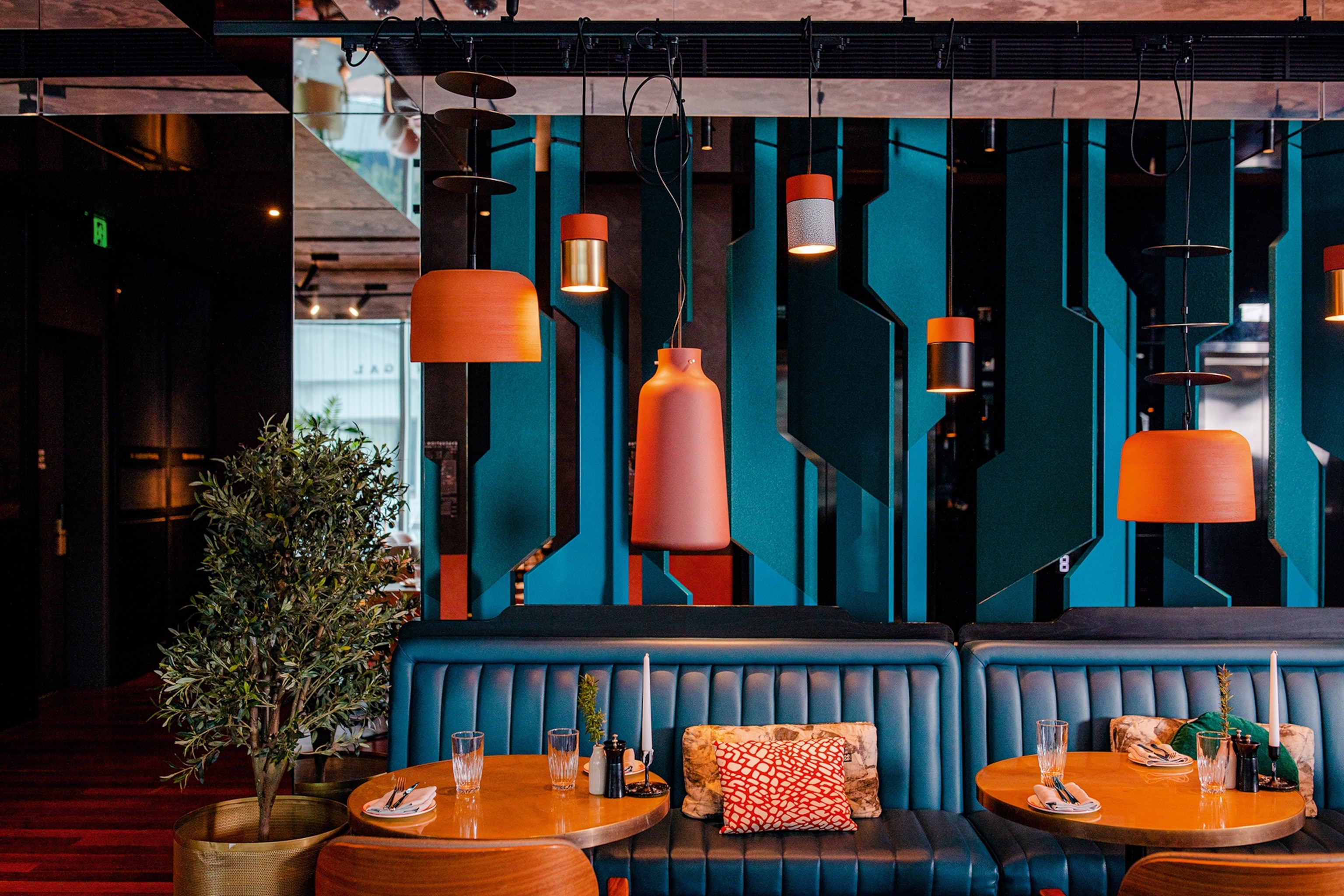 Restaurant with navy leather sofas, orange sofa cushions and hanging lights with orange lampshades