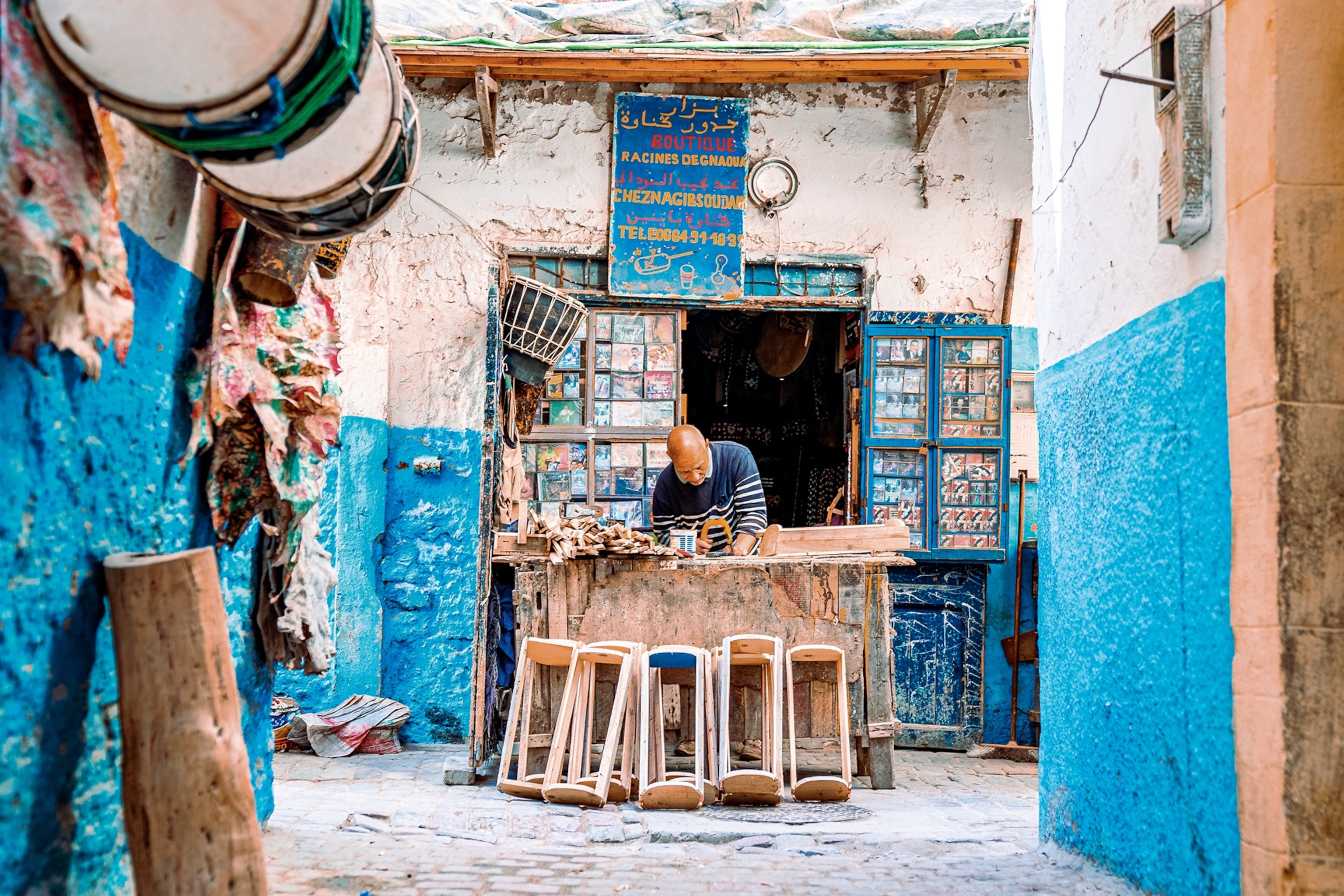A woodcarver in his shop in the medina, surrounded by his work.