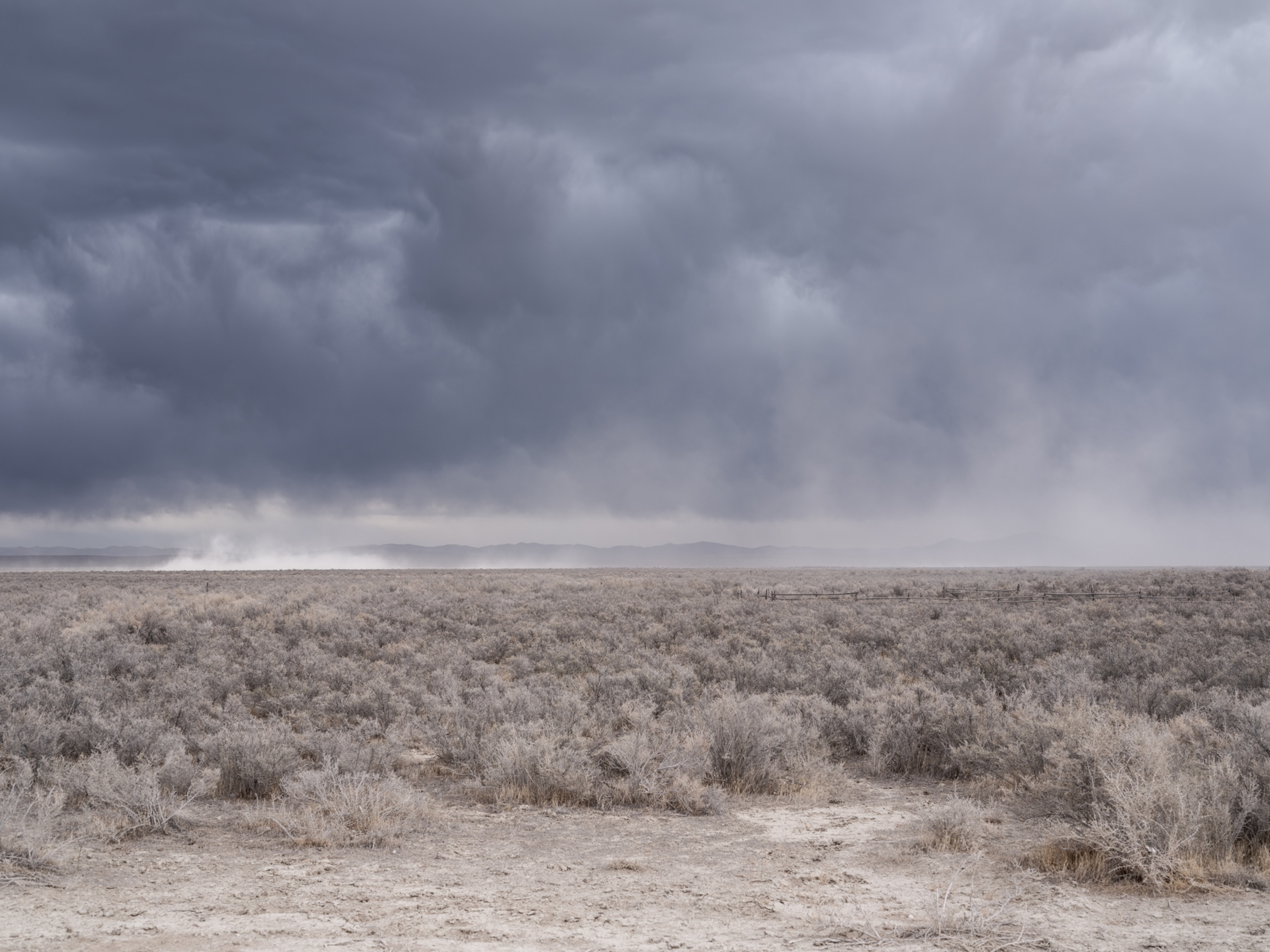 Dry prairie landscape under stormy skies.