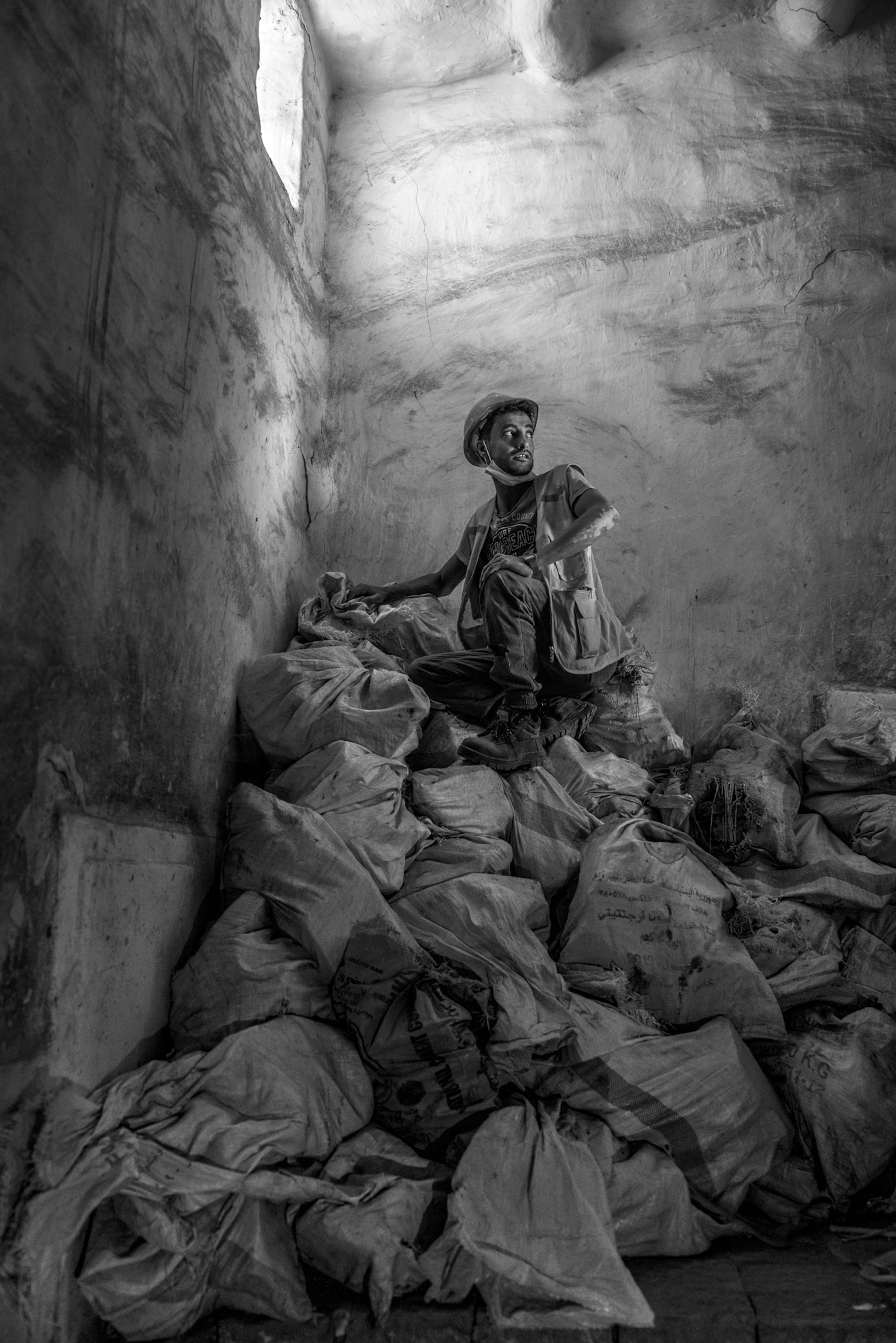 Picture of man hard hat atop of pile of bags.