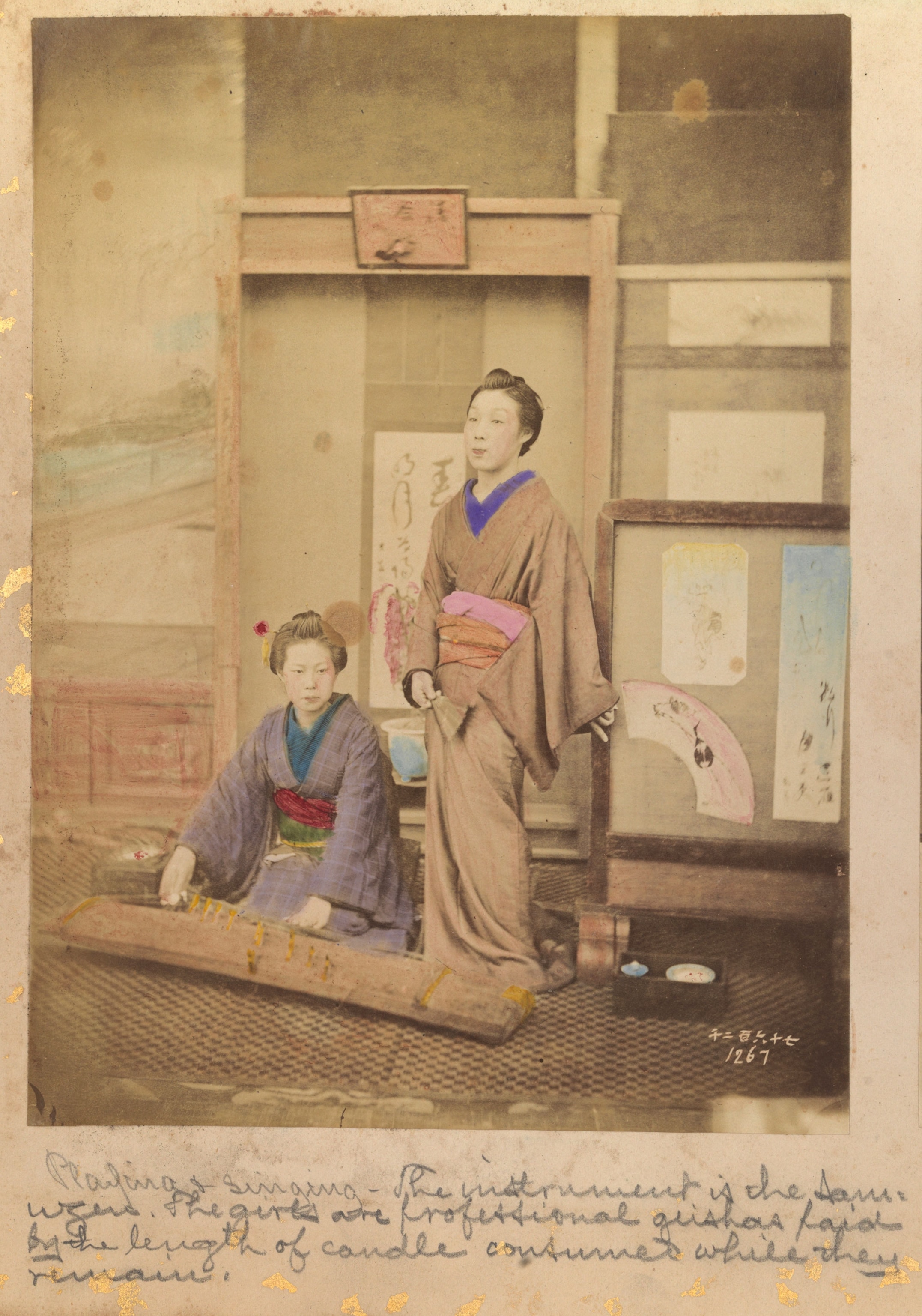 A historic photo of two Geisha entertaining by playing the koto and singing in Japan in the 1880s