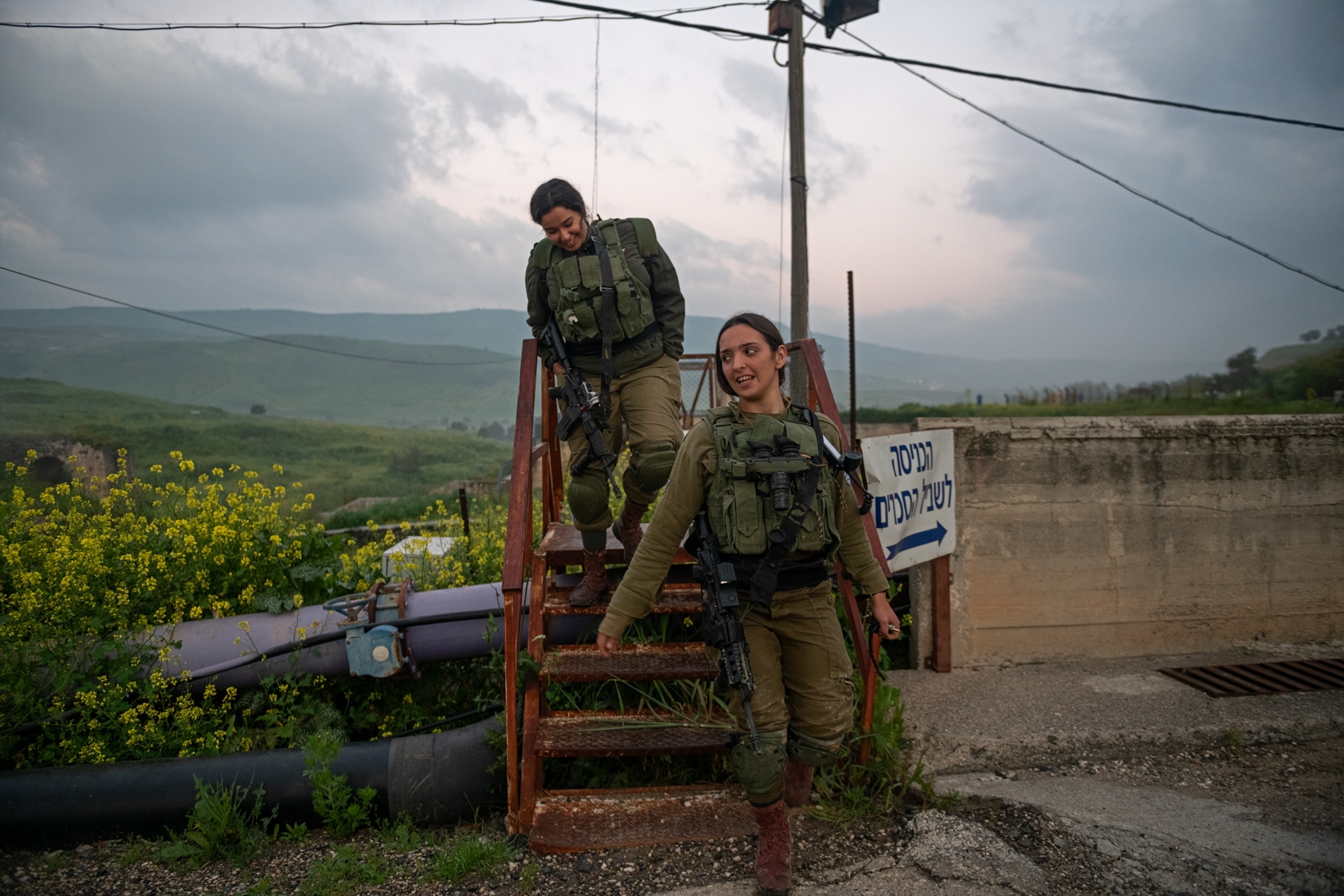 two women walking down a set of stairs in front of a field