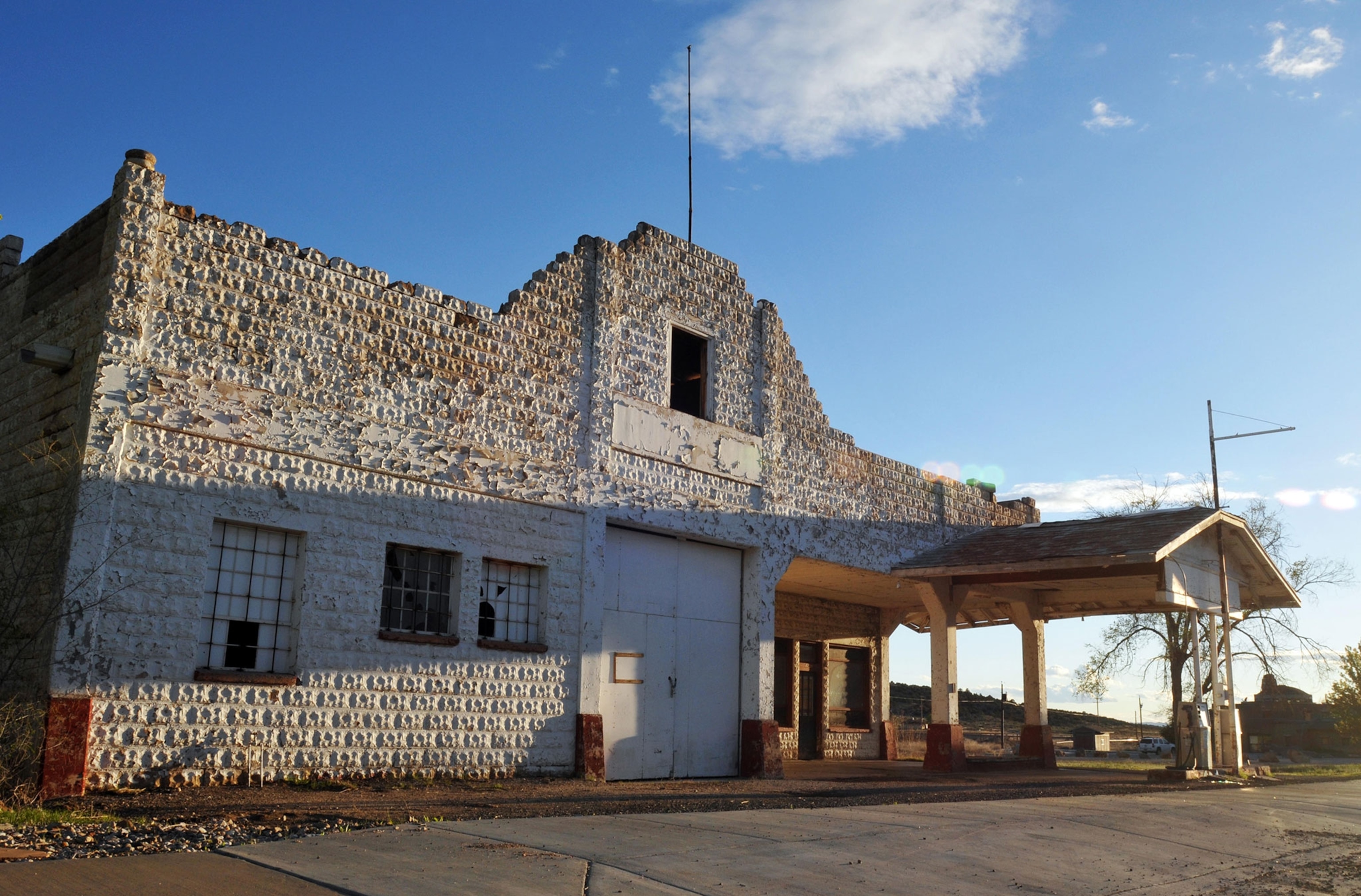 The late-afternoon sun shines on the historic Osterman Shell gas station, all in white brick, in the desert.