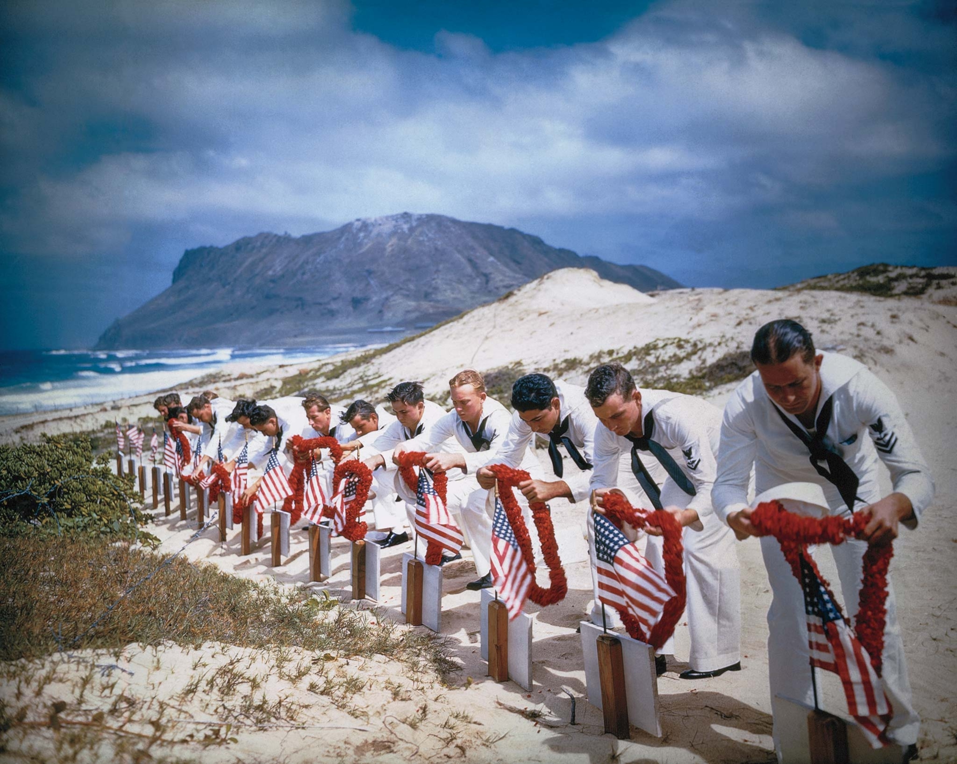Enlisted men of the Naval Air Station at Kaneohe, Hawaii, place leis on the graves of their comrades killed in the Japanese attack on Pearl Harbor.