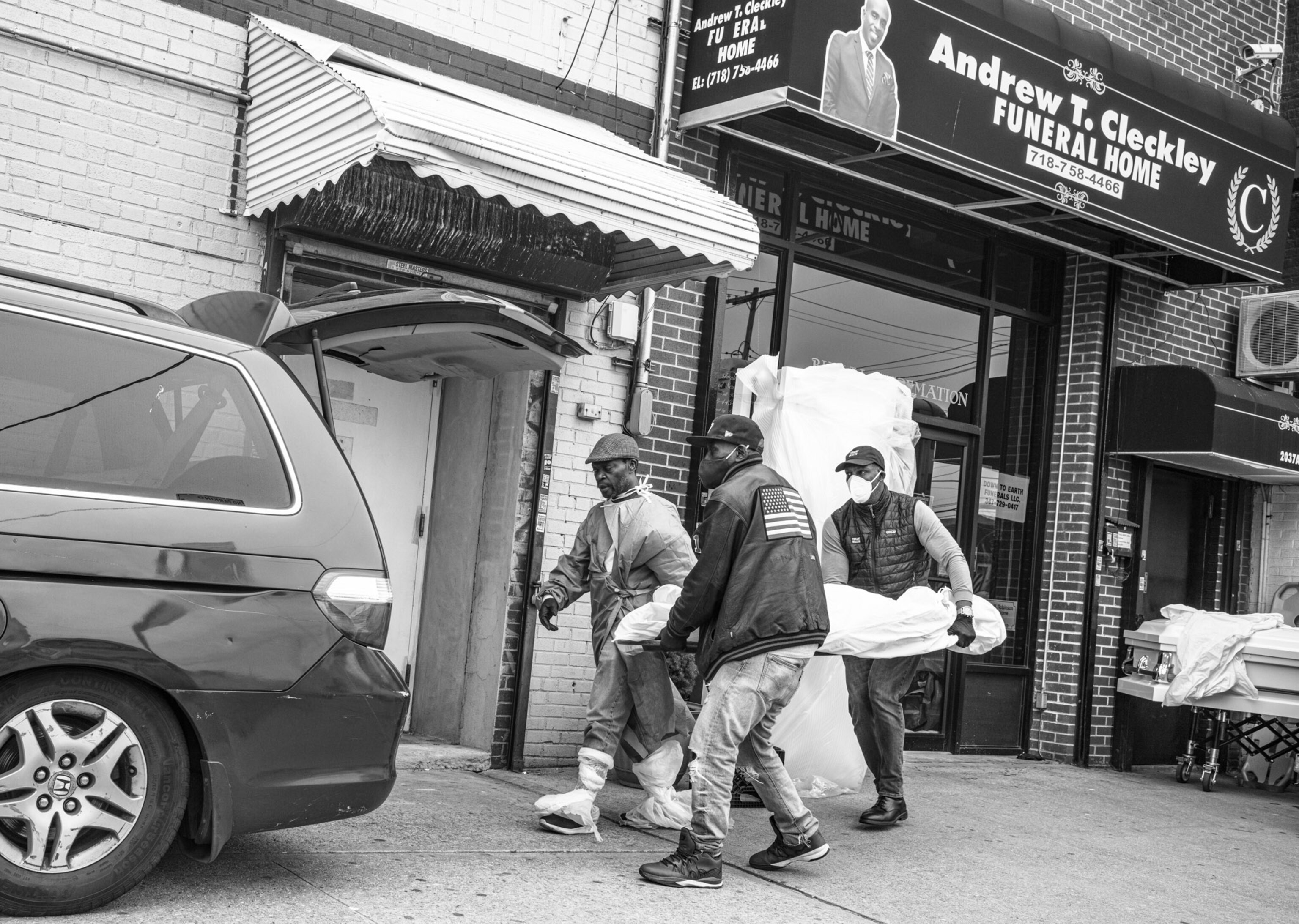 three people putting a wrapped body into a car