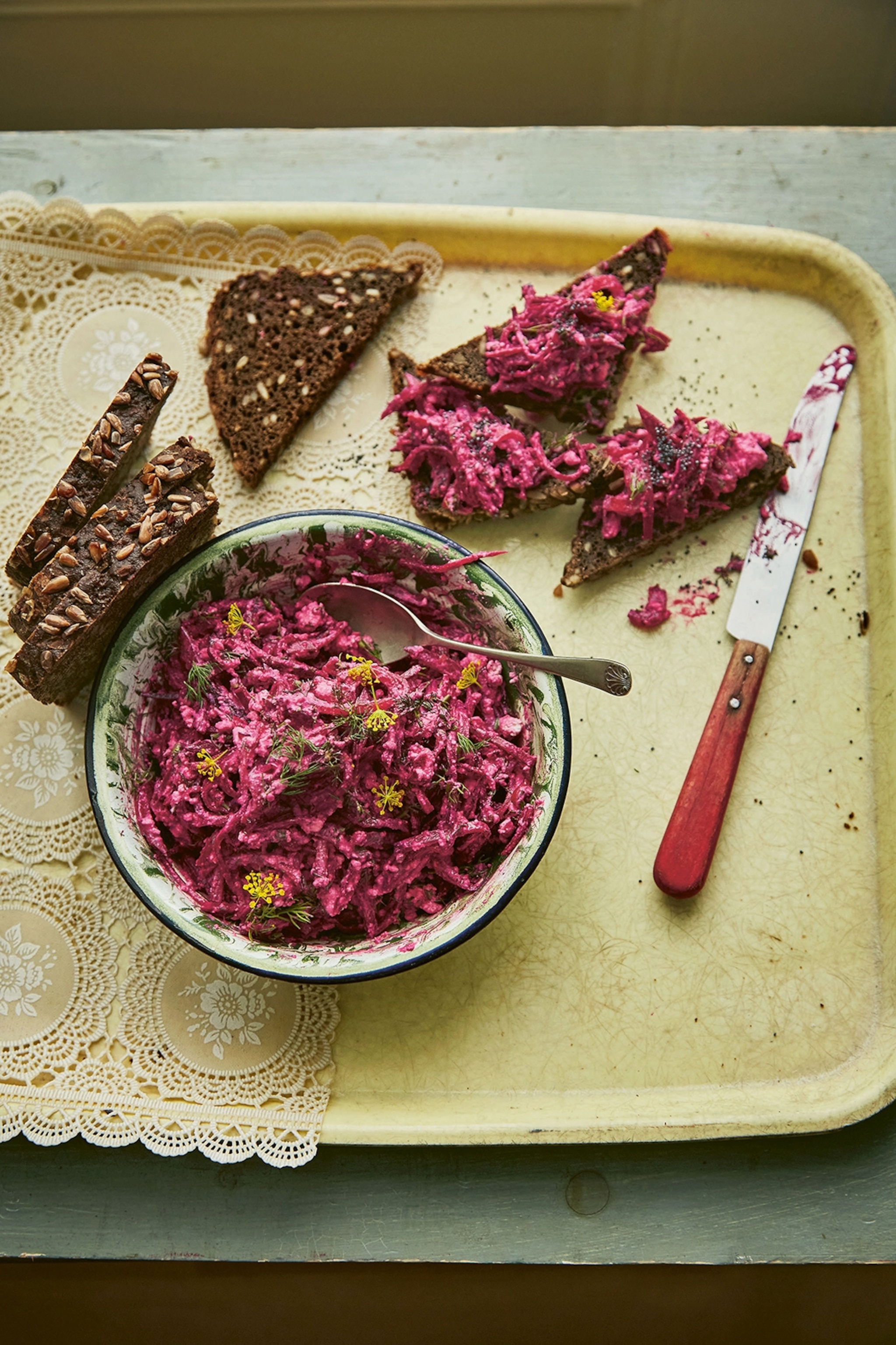 A plastic tray with a bowl of bright cabbage slaw and cheese, rye bread on the side.