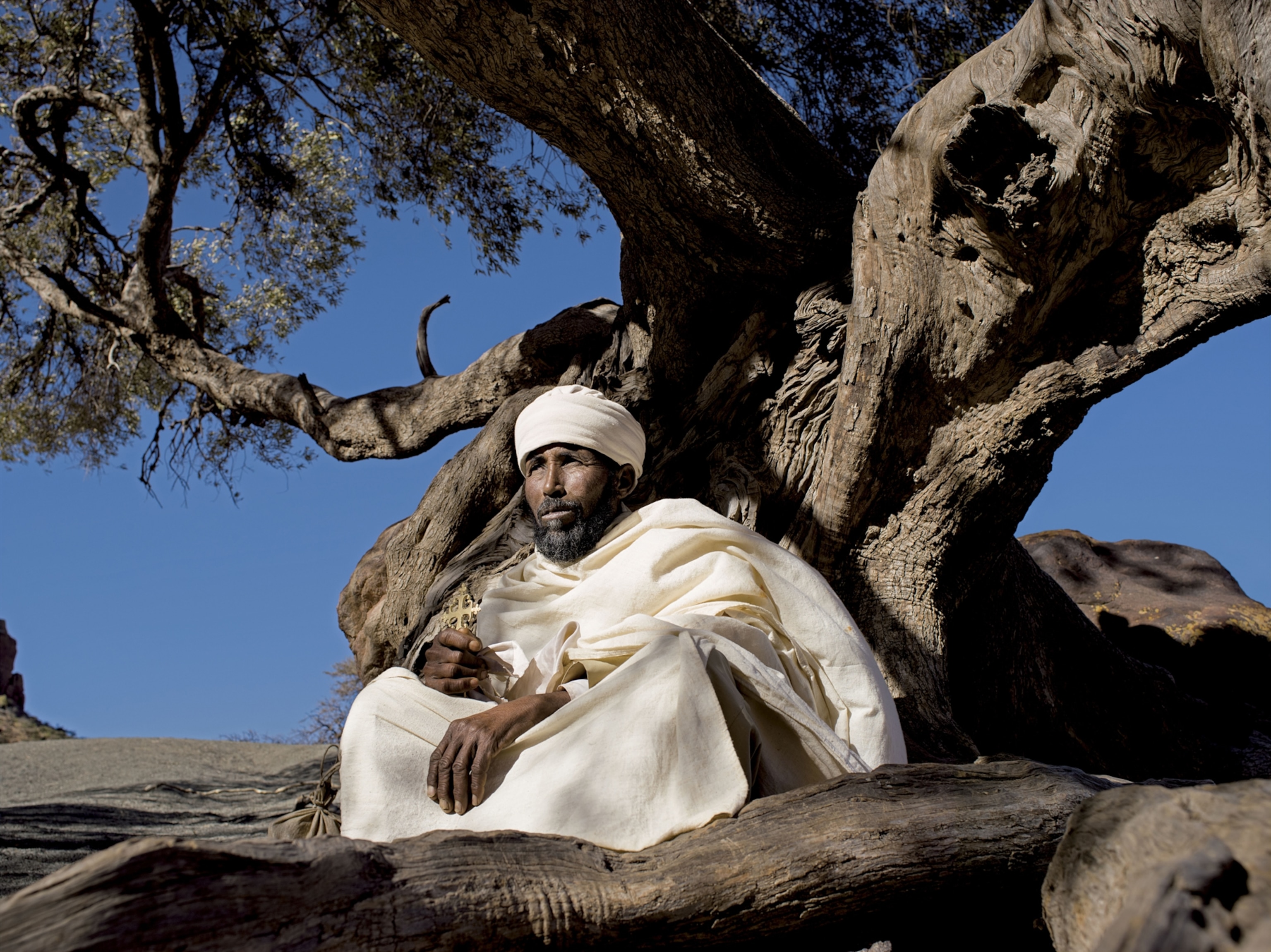 an Ethiopian resident priest of Abuna Yemata Guh resting under a sacred olive tree